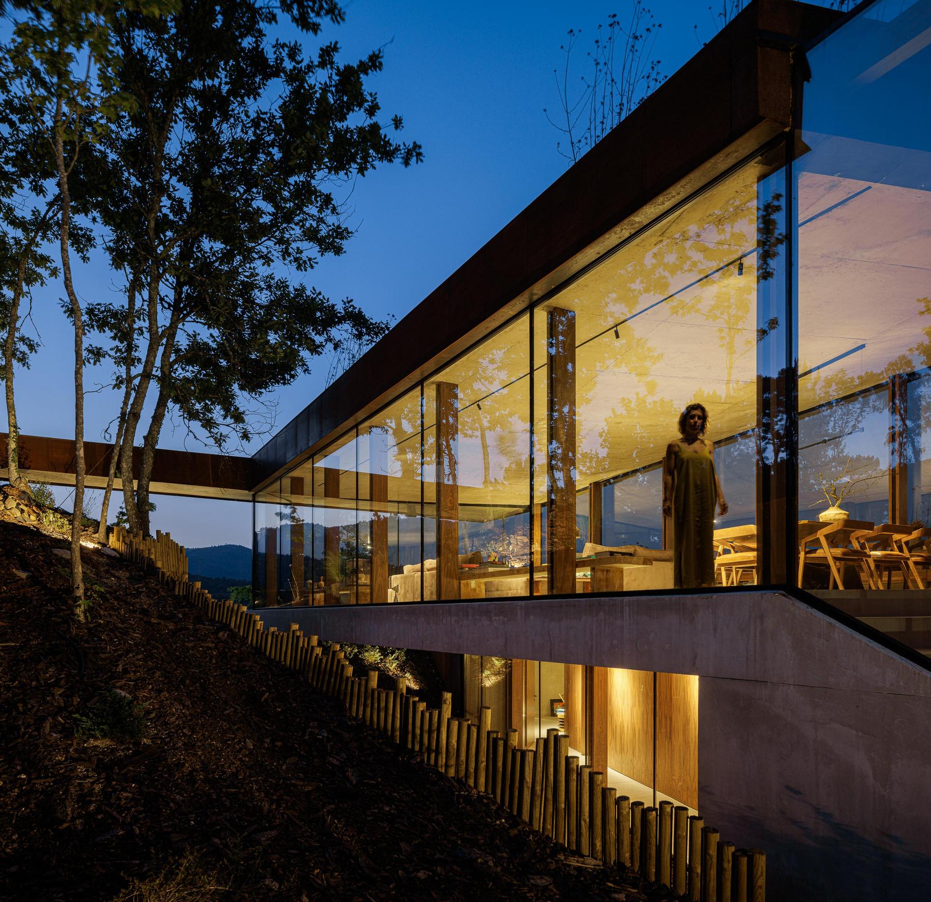Exterior: Vista geral da casa Corten, com revestimento em aço corten e amplas janelas, integrada na paisagem natural. — Casa Corten arquitetura HPA Arquitetura e Investimentos em Celorico de Basto