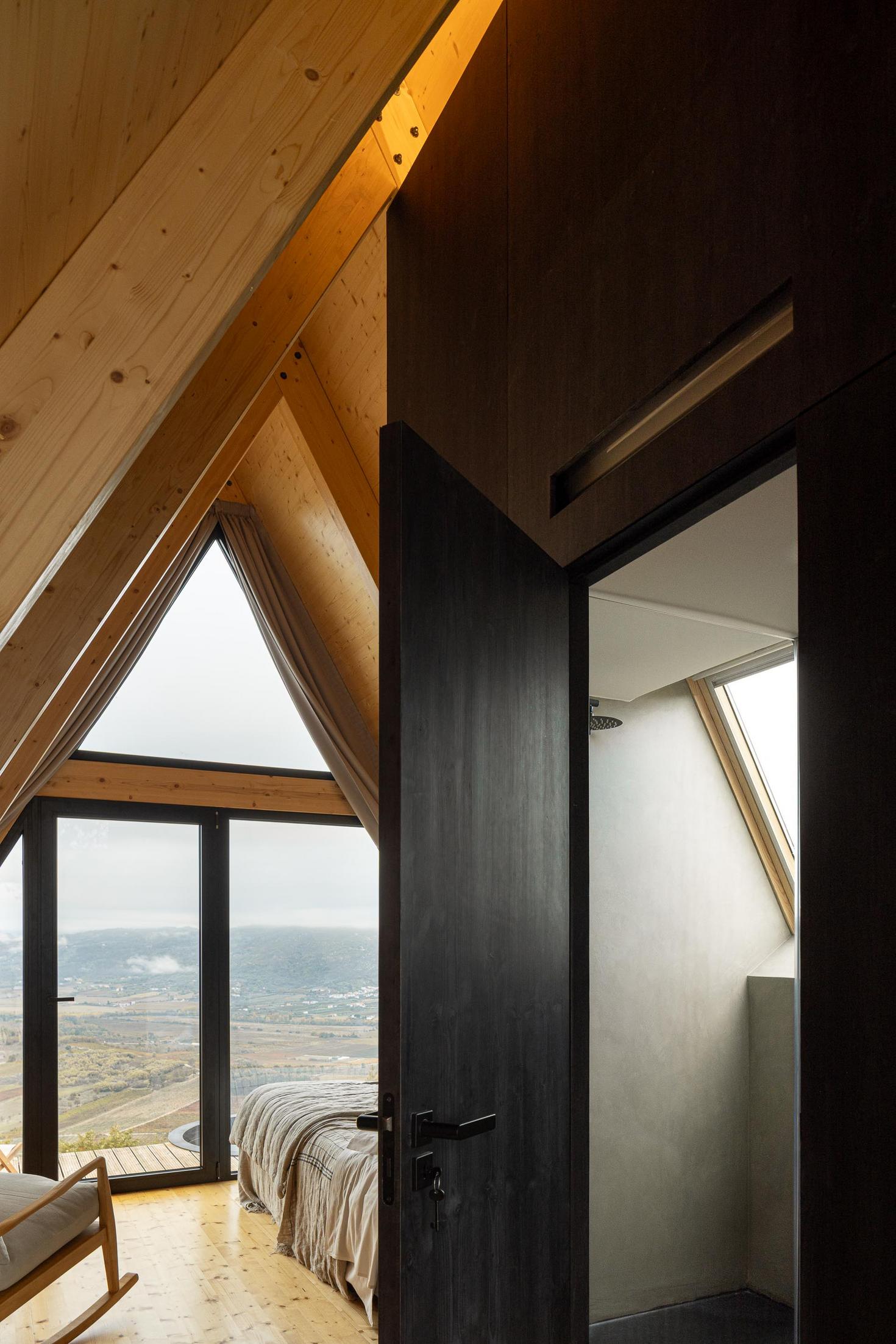 Quarto com cama, casa de banho com duche e vista para a paisagem. Estrutura de madeira aparente. — Abrigos de Montanha arquitetura Filipe Pina Arquitectura em Belmonte