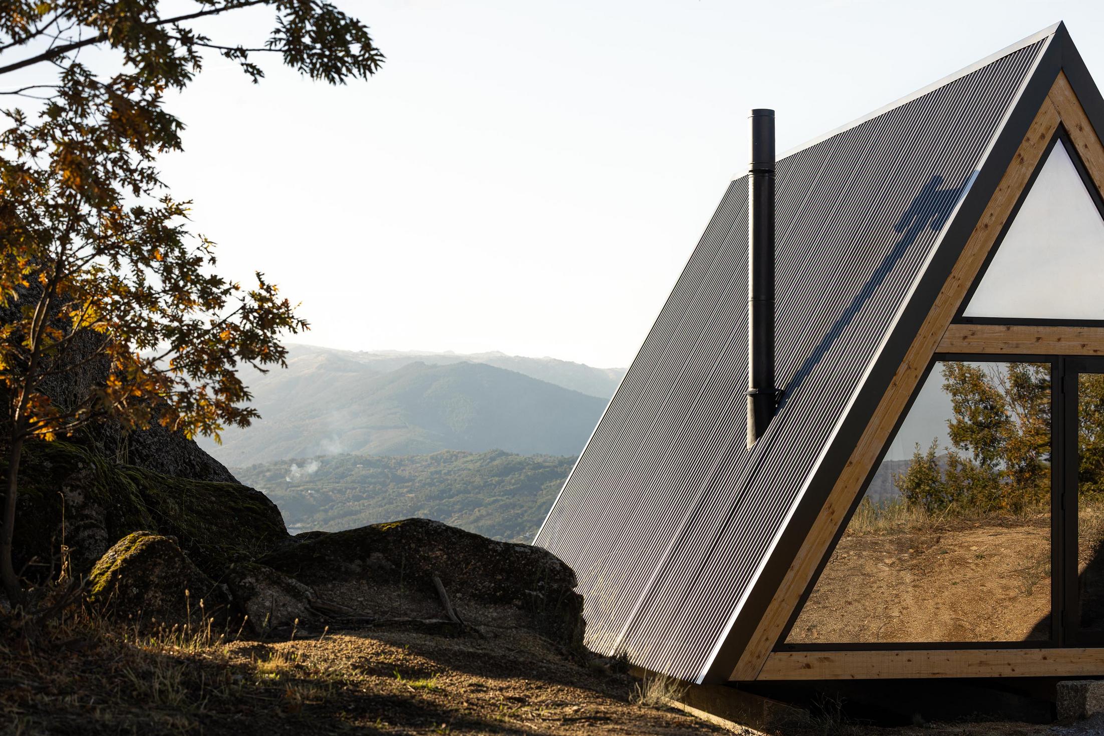 Exterior da cabana triangular com revestimento metálico e estrutura de madeira, inserida na paisagem montanhosa. — Abrigos de Montanha arquitetura Filipe Pina Arquitectura em Belmonte