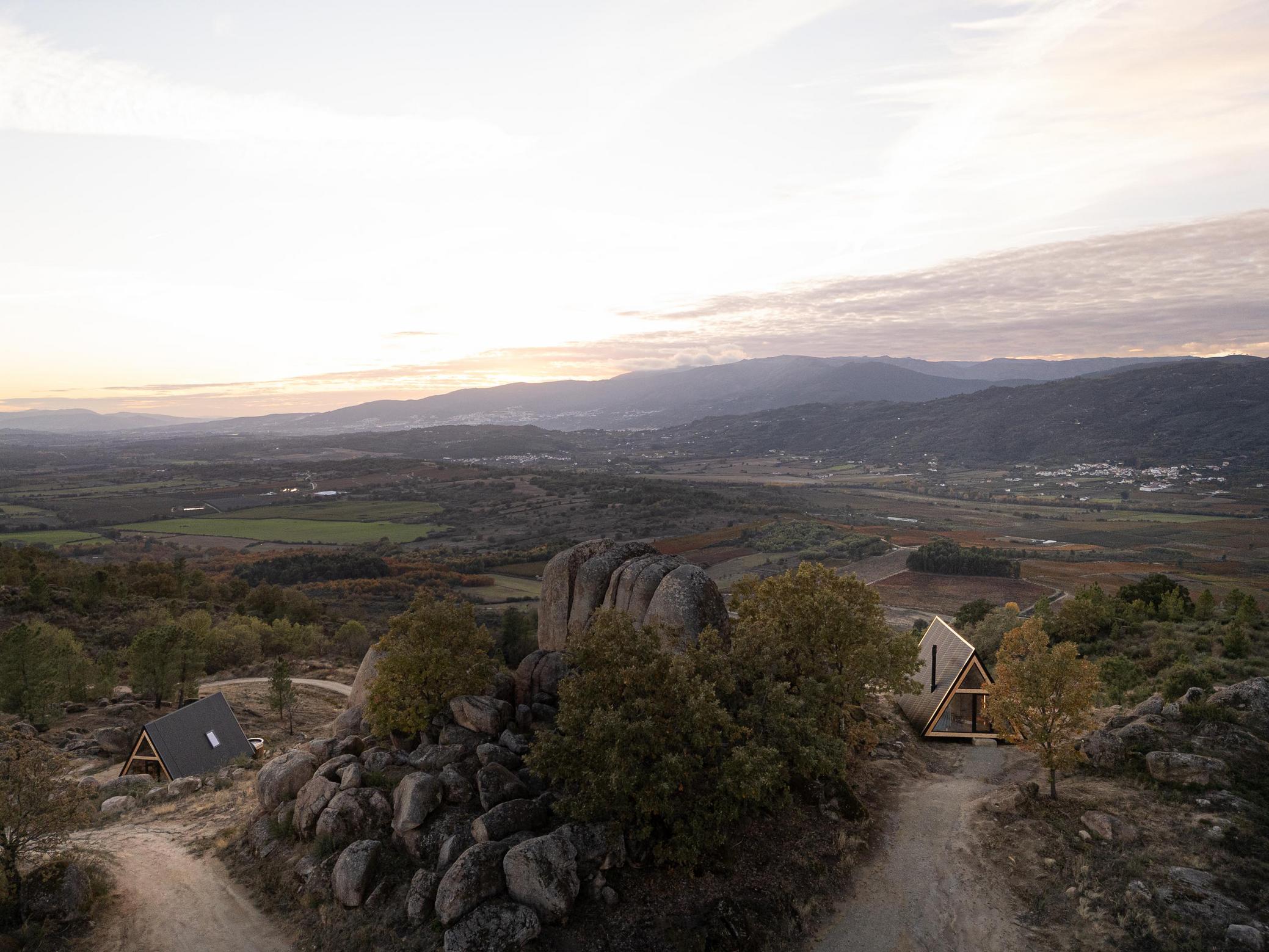 Vista aérea das duas cabanas triangulares inseridas na paisagem rochosa e montanhosa. — Abrigos de Montanha arquitetura Filipe Pina Arquitectura em Belmonte