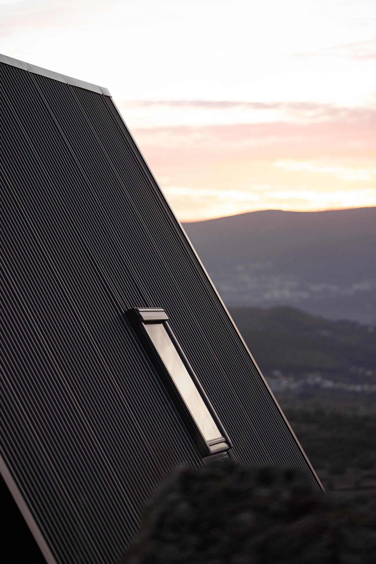 Exterior da cabana com detalhe da claraboia no revestimento metálico. Paisagem montanhosa ao fundo. — Abrigos de Montanha arquitetura Filipe Pina Arquitectura em Belmonte