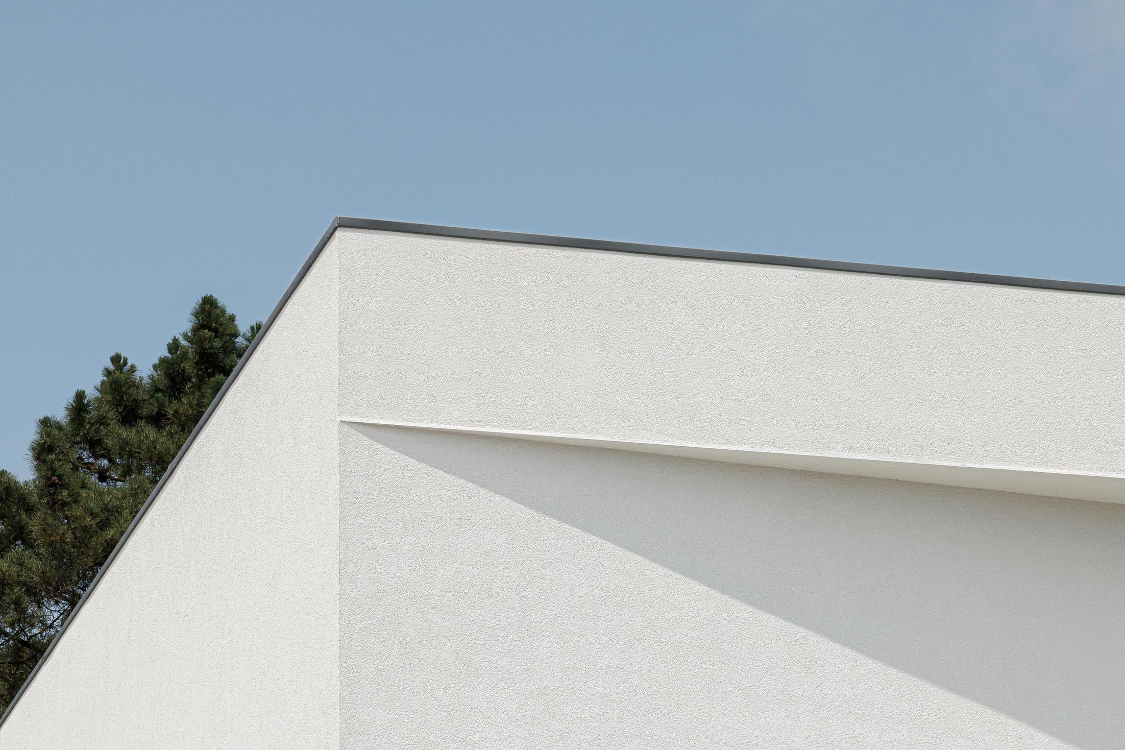 Exterior: Detalhe da esquina da moradia branca com céu azul e pinheiro. — Casa dos Sobreiros II arquitetura Urbanpolis em Póvoa de Varzim