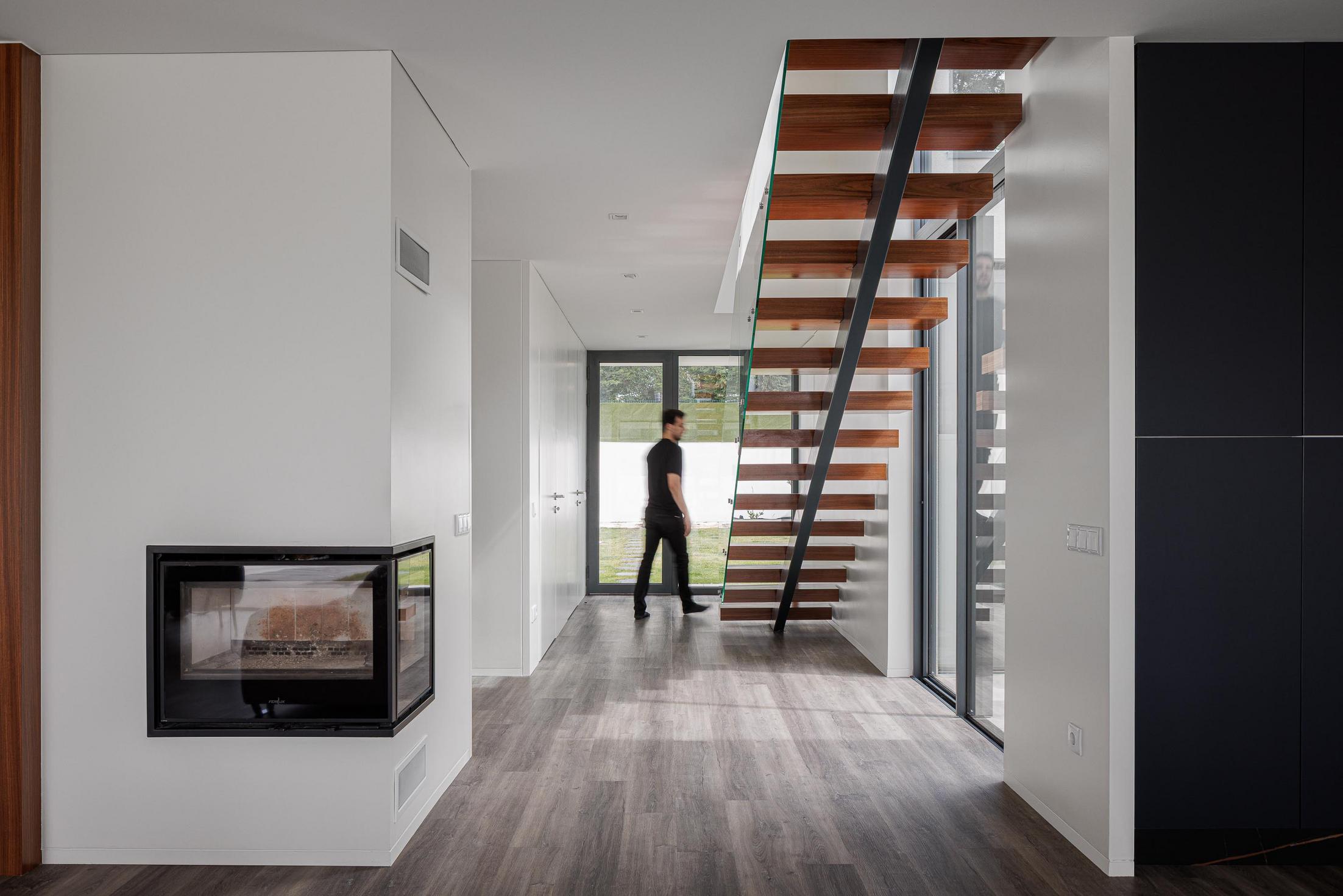 Hall de entrada: Escada flutuante, lareira moderna e pavimento em madeira. — Casa dos Sobreiros II arquitetura Urbanpolis em Póvoa de Varzim