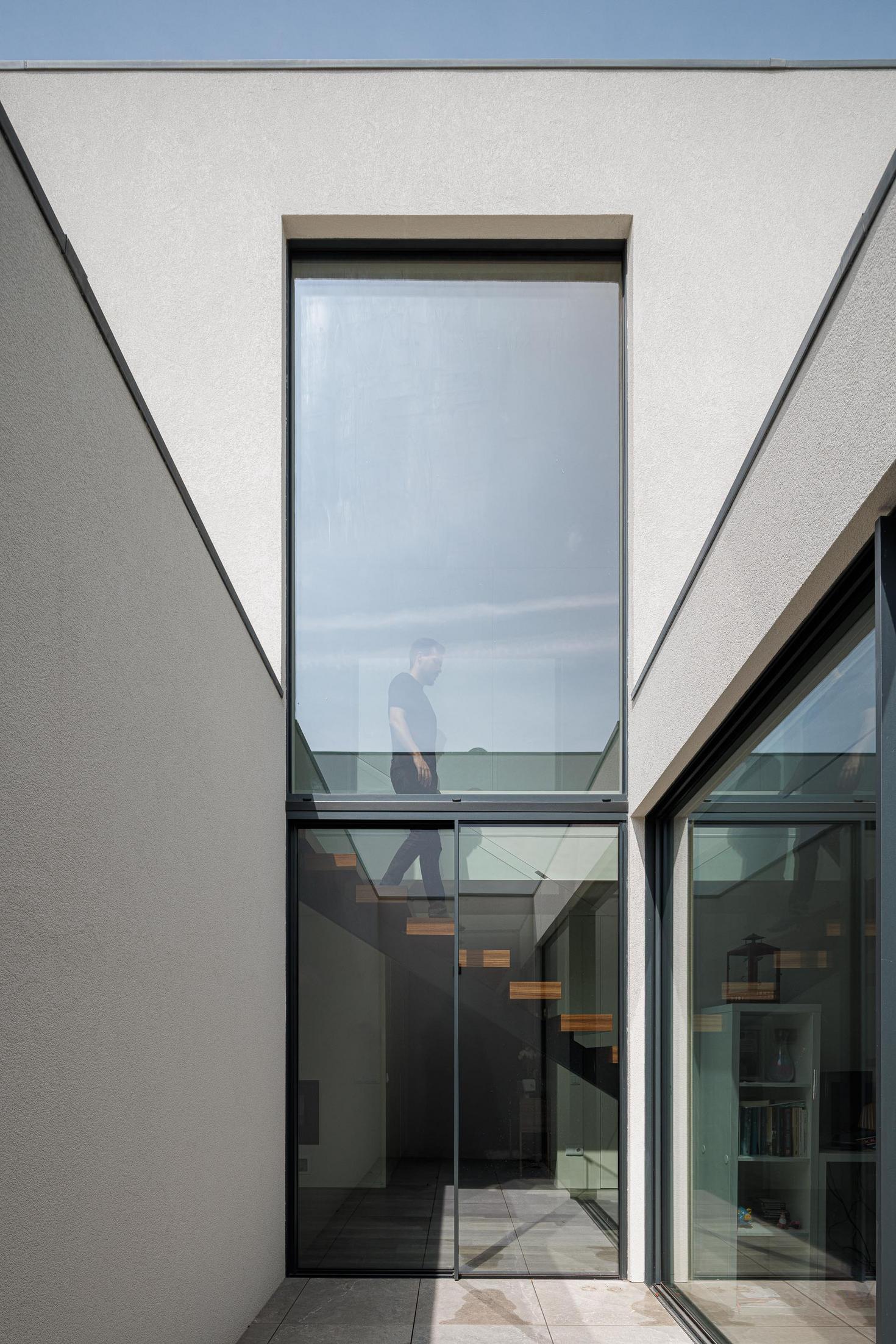 Escada: Escada flutuante com grande janela vertical e pátio exterior. — Casa dos Sobreiros II arquitetura Urbanpolis em Póvoa de Varzim