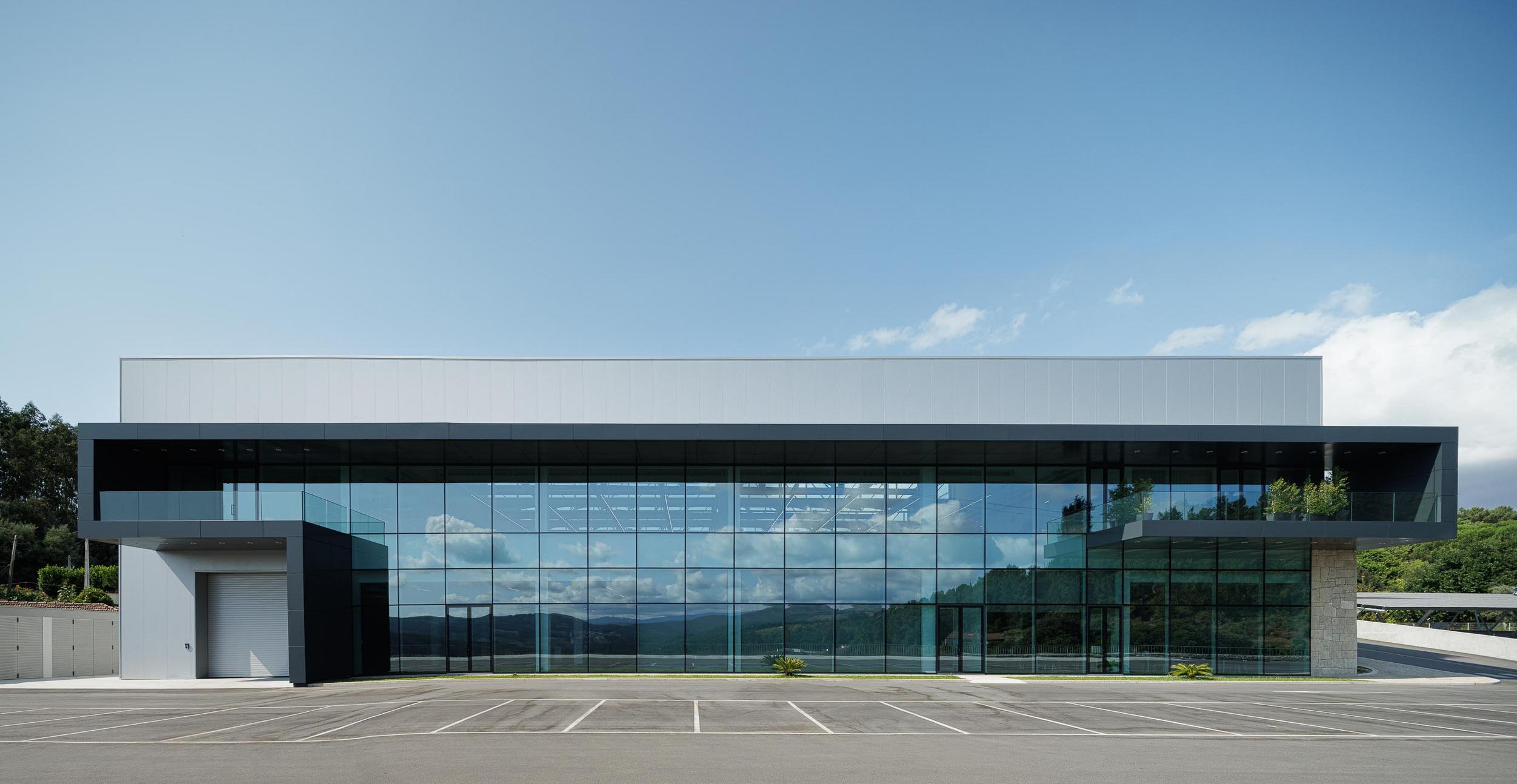 Fachada principal: Vista frontal do edifício com grandes janelas e entrada lateral. — Bradco II arquitetura Em Paralelo em Castelo de Paiva