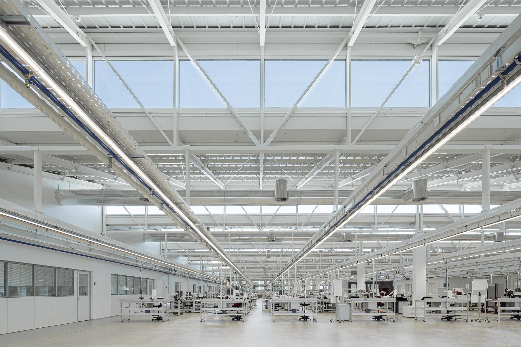 Fábrica: Espaço amplo com estrutura metálica aparente e iluminação industrial. — Bradco II arquitetura Em Paralelo em Castelo de Paiva