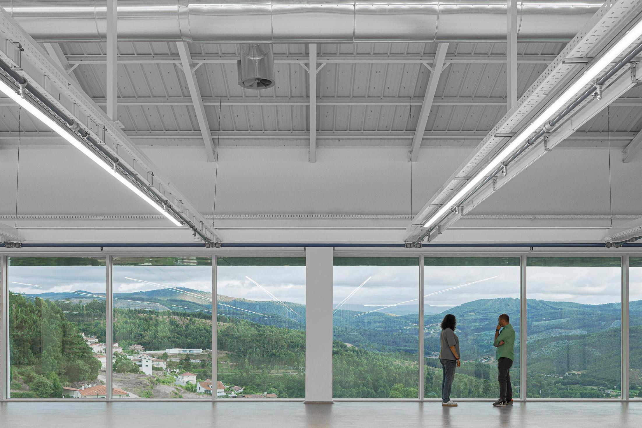 Fábrica: Detalhe da bancada de laboratório com vista para a área de produção. — Bradco II arquitetura Em Paralelo em Castelo de Paiva