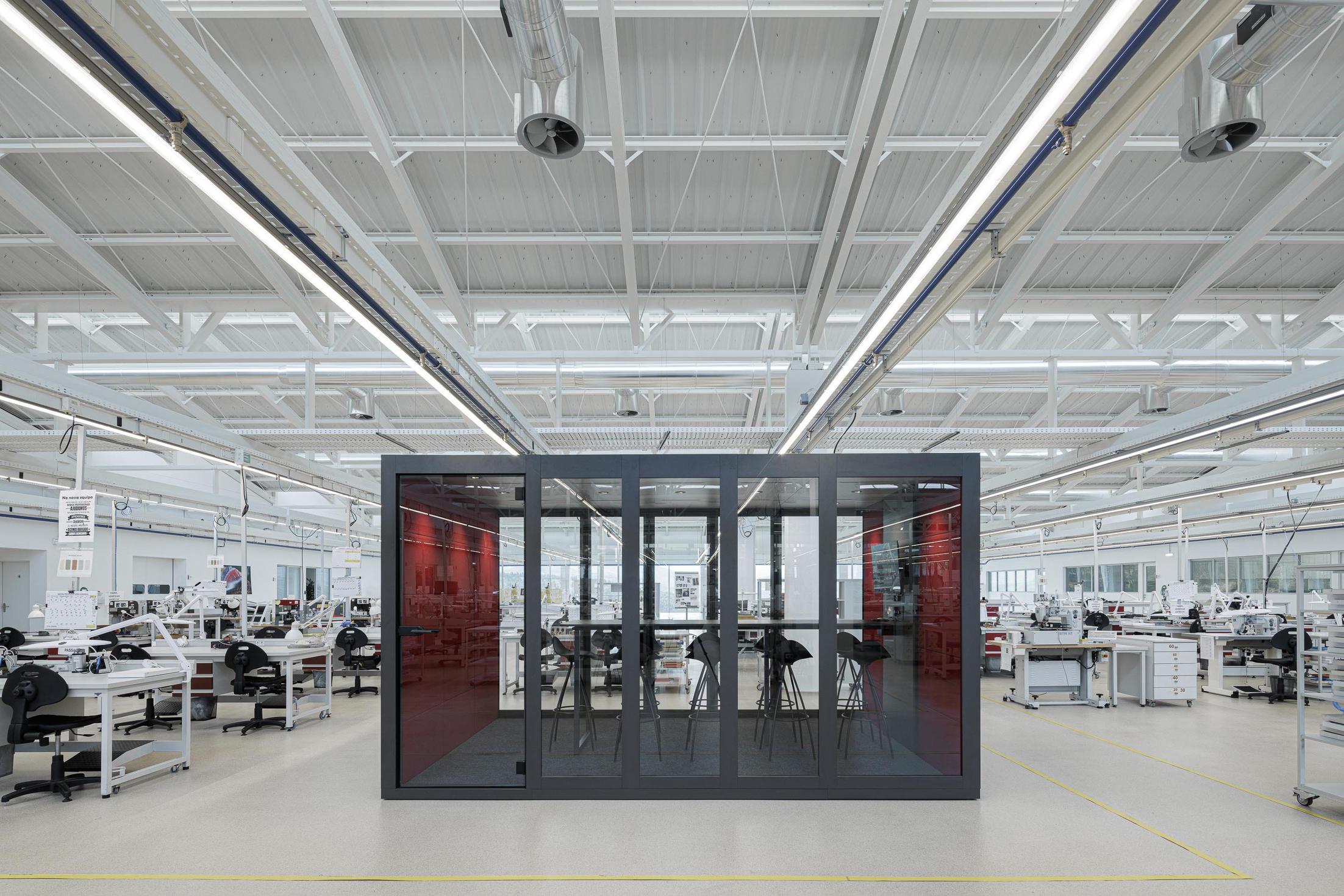 Fábrica: Espaço industrial com máquinas, tubagens e colunas brancas. — Bradco II arquitetura Em Paralelo em Castelo de Paiva