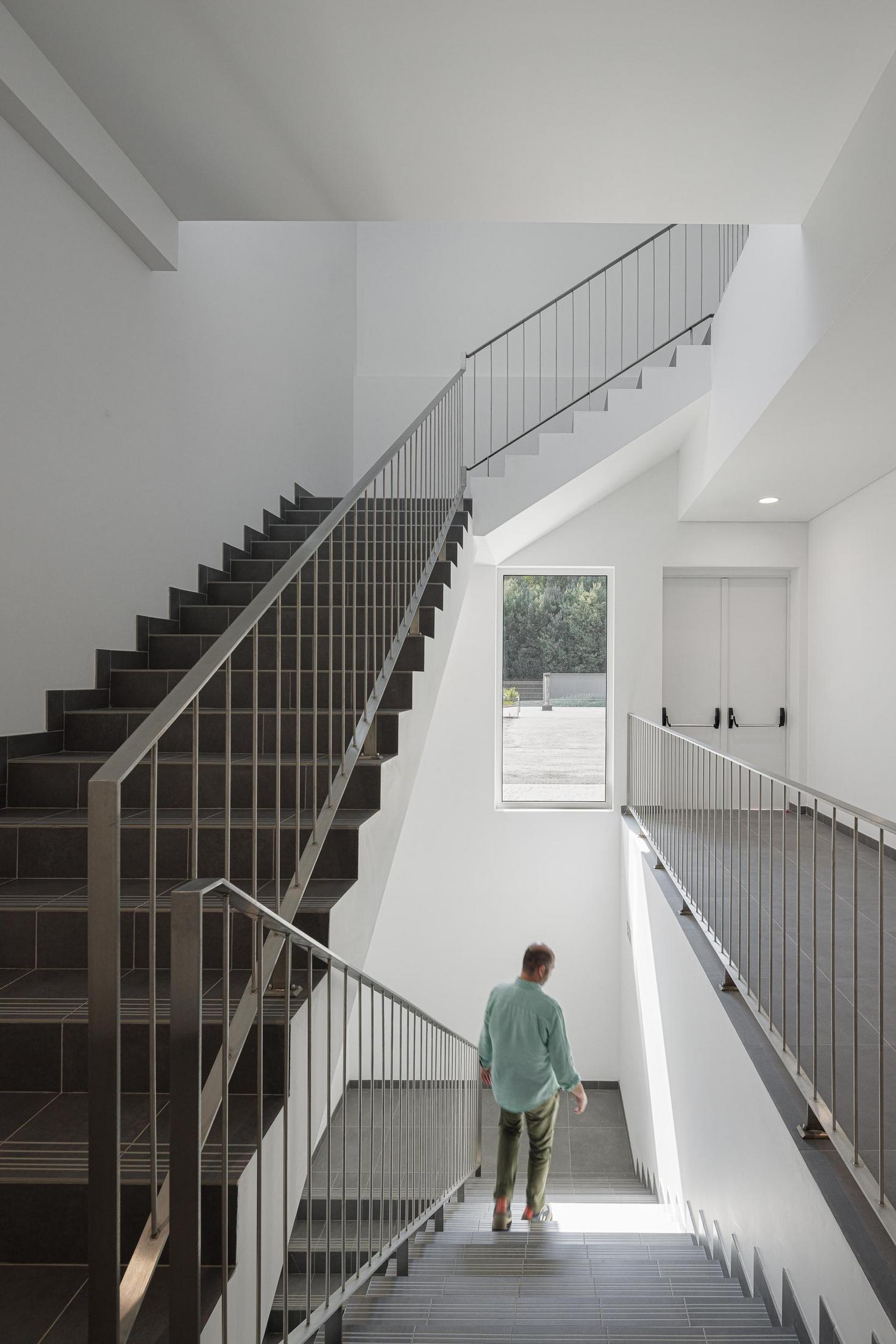 Fachada lateral: Detalhe da fachada com revestimento escuro e pilares em pedra. — Bradco II arquitetura Em Paralelo em Castelo de Paiva