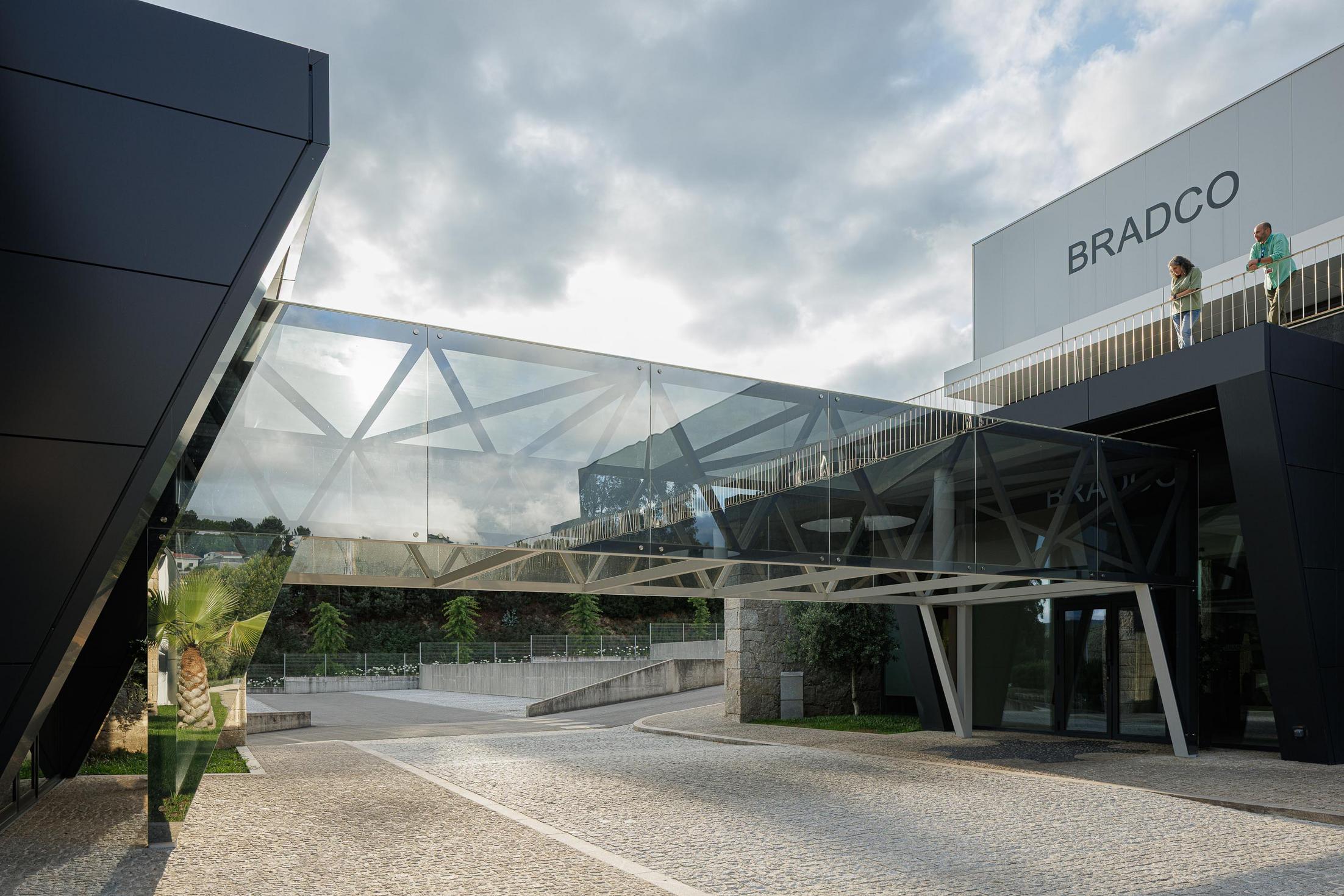 Fachada principal: Edifício industrial com fachada envidraçada e iluminação interior. — Bradco II arquitetura Em Paralelo em Castelo de Paiva