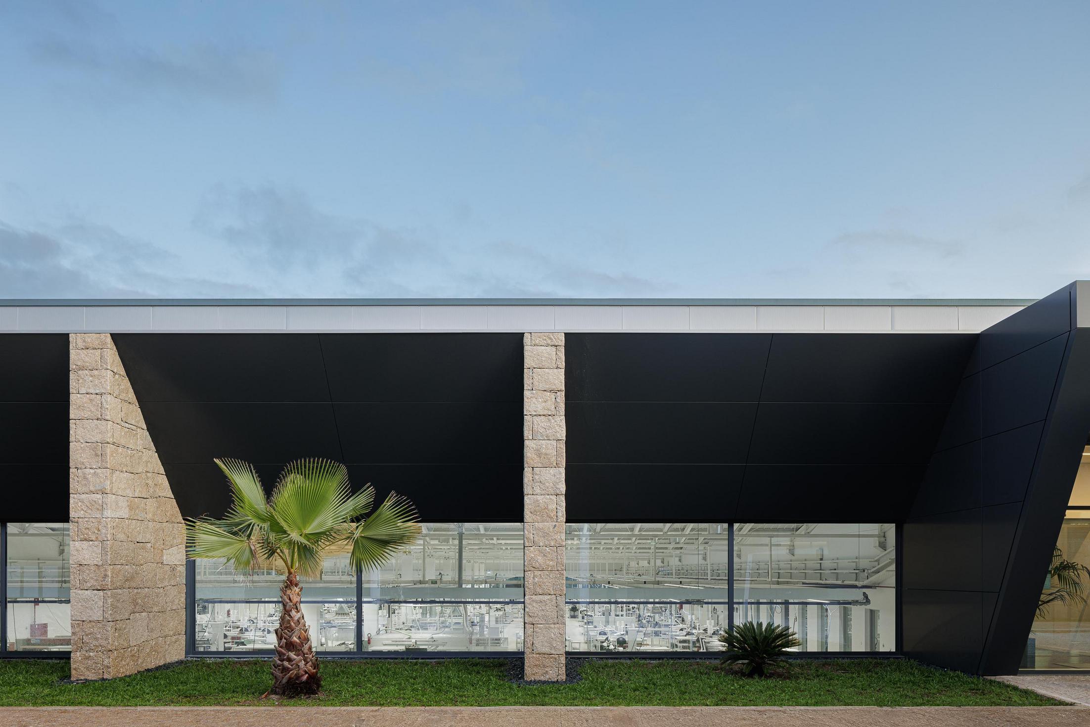 Fachada principal: Vista frontal da fachada envidraçada com iluminação interior. — Bradco II arquitetura Em Paralelo em Castelo de Paiva