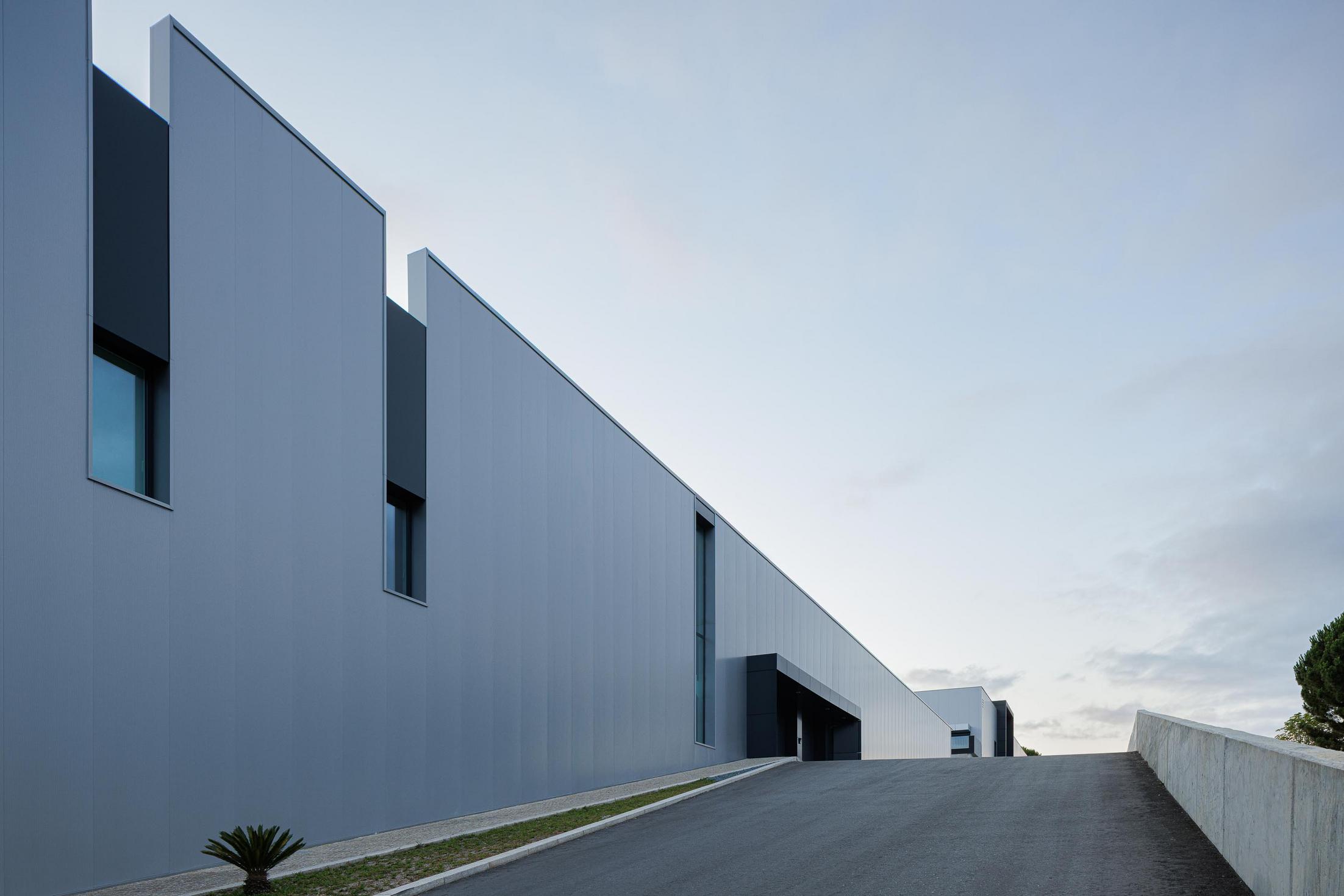 Fachada principal: Detalhe da fachada envidraçada com iluminação interior. — Bradco II arquitetura Em Paralelo em Castelo de Paiva