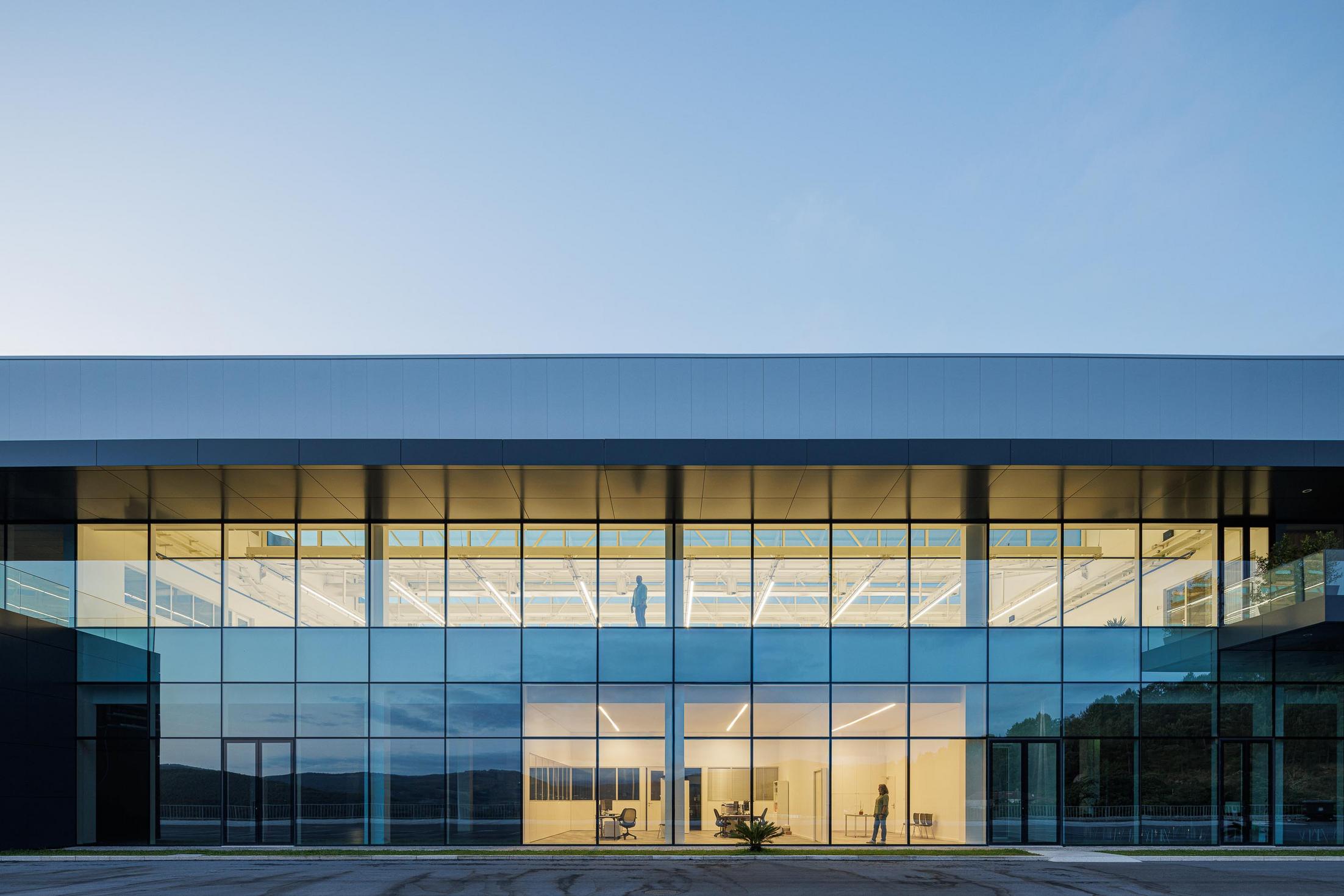 Entrada principal: Vista noturna da entrada com passarela e iluminação. — Bradco II arquitetura Em Paralelo em Castelo de Paiva