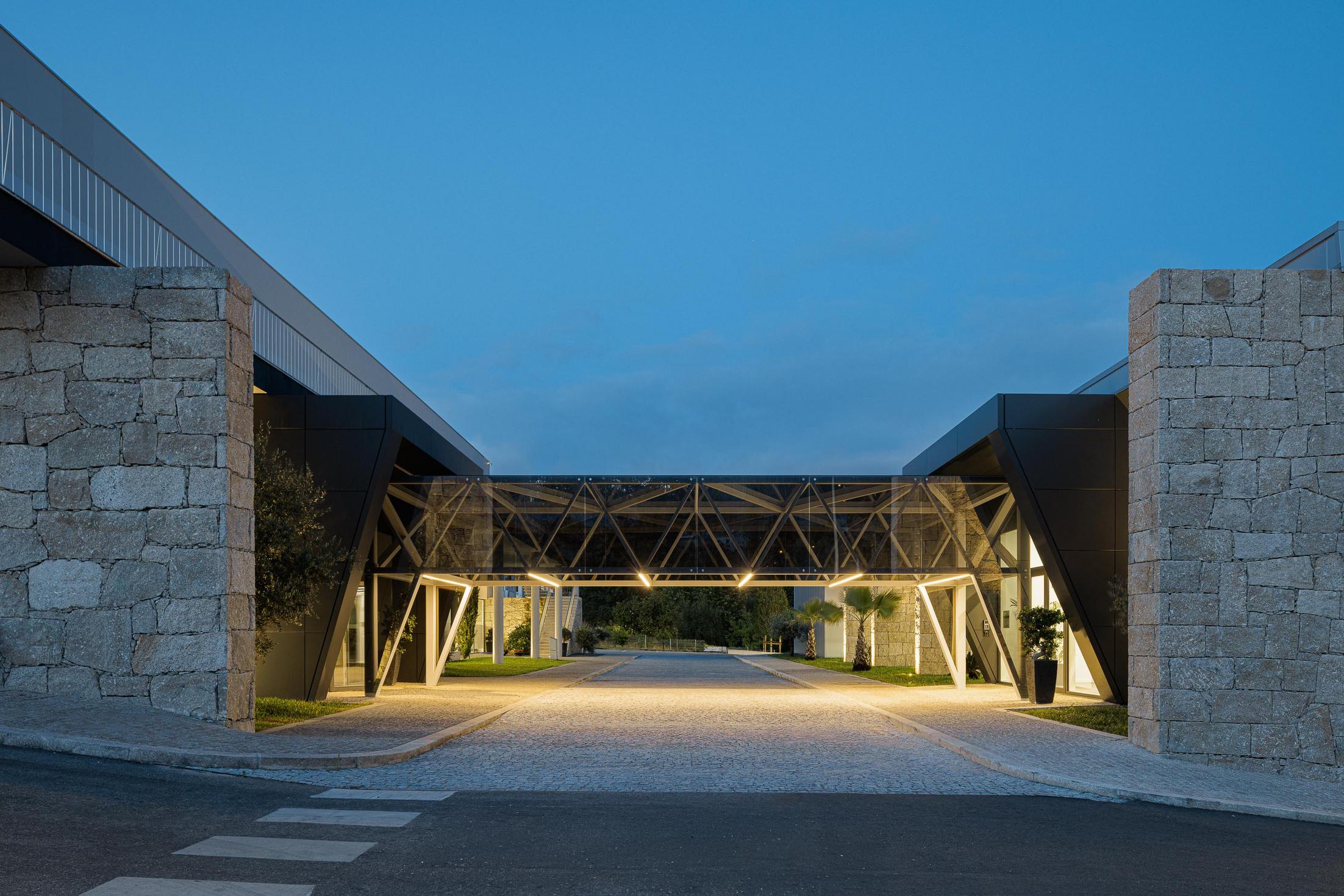 Fábrica: Vista noturna do interior da fábrica com iluminação industrial. — Bradco II arquitetura Em Paralelo em Castelo de Paiva