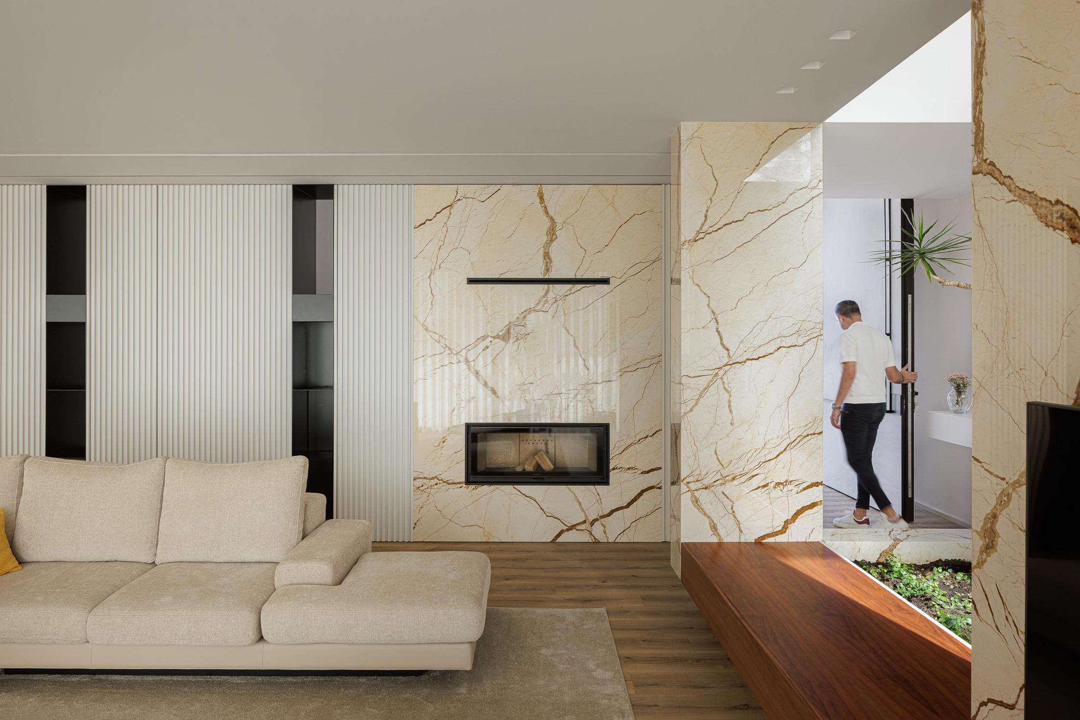 Sala de estar: Sofá bege, lareira em mármore e jardim interior com vegetação. — Casa Branca Minimalista arquitetura Arquitetura501 em Braga