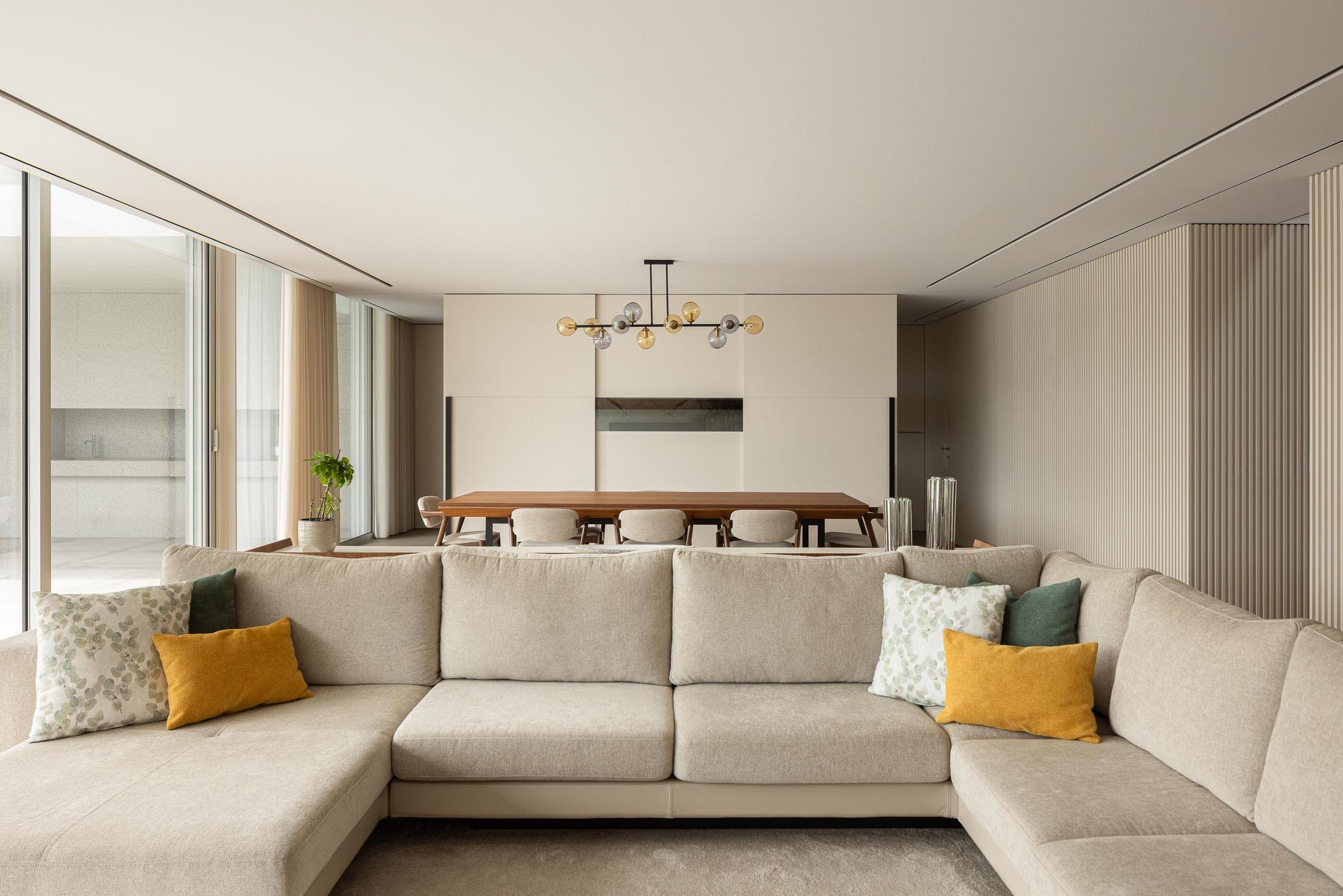 Sala de estar/Jantar: Sofá bege, mesa de jantar em madeira e candeeiro suspenso. — Casa Branca Minimalista arquitetura Arquitetura501 em Braga