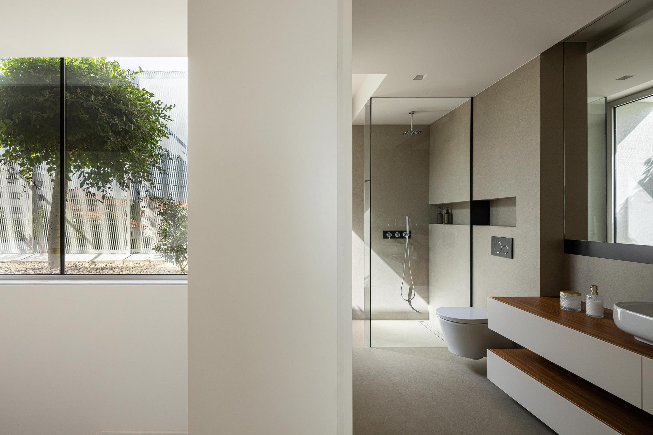Casa de banho: Cabine de duche em vidro, lavatório sobre móvel branco e janela com vista. — Casa Branca Minimalista arquitetura Arquitetura501 em Braga