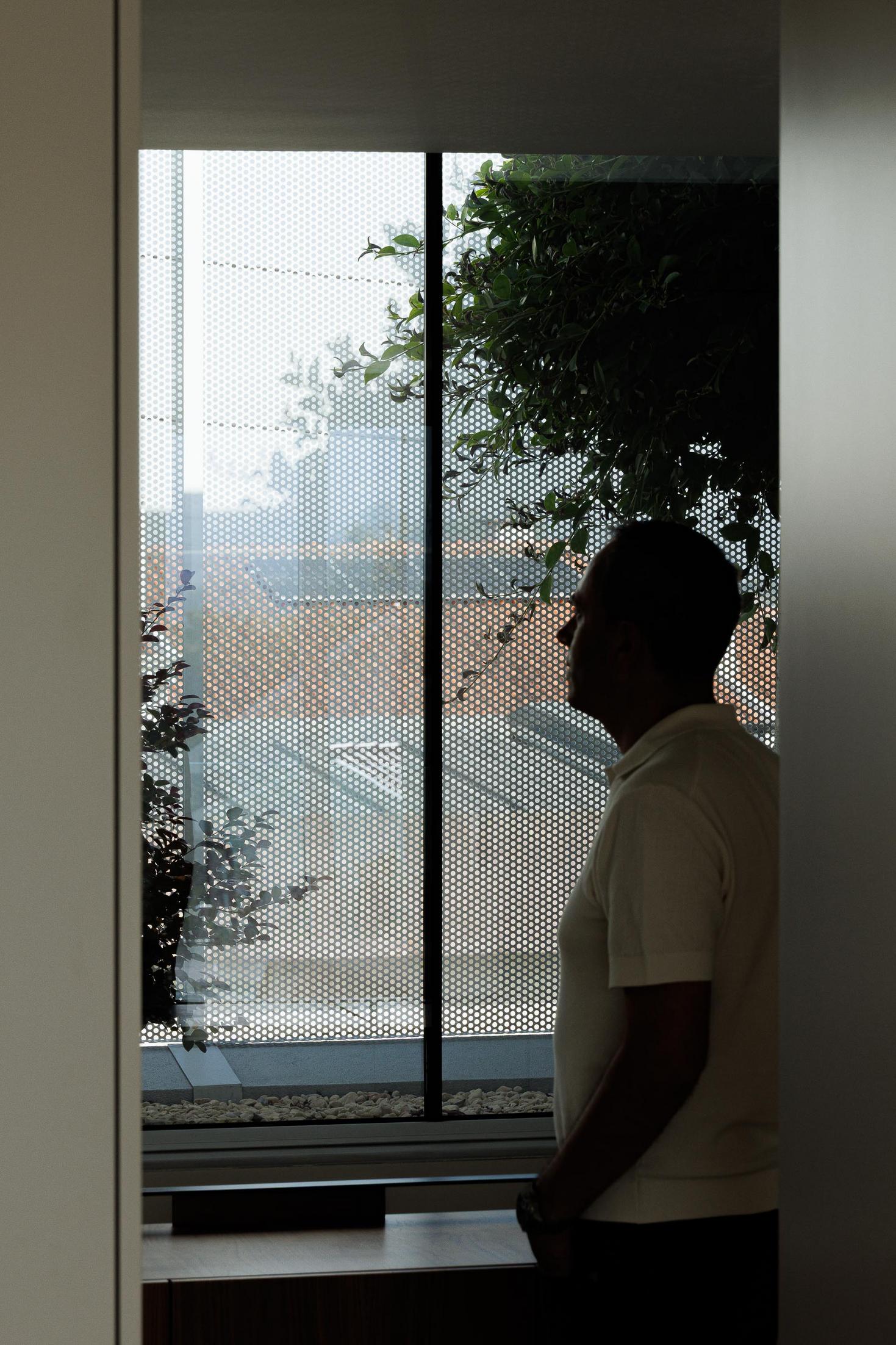Exterior: Detalhe da fachada superior com revestimento metálico perfurado e vegetação. — Casa Branca Minimalista arquitetura Arquitetura501 em Braga