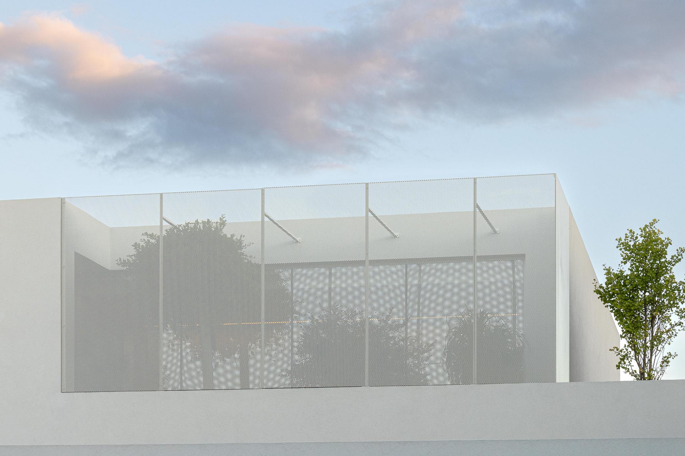 Exterior: Detalhe da fachada superior com revestimento metálico perfurado e vegetação. — Casa Branca Minimalista arquitetura Arquitetura501 em Braga
