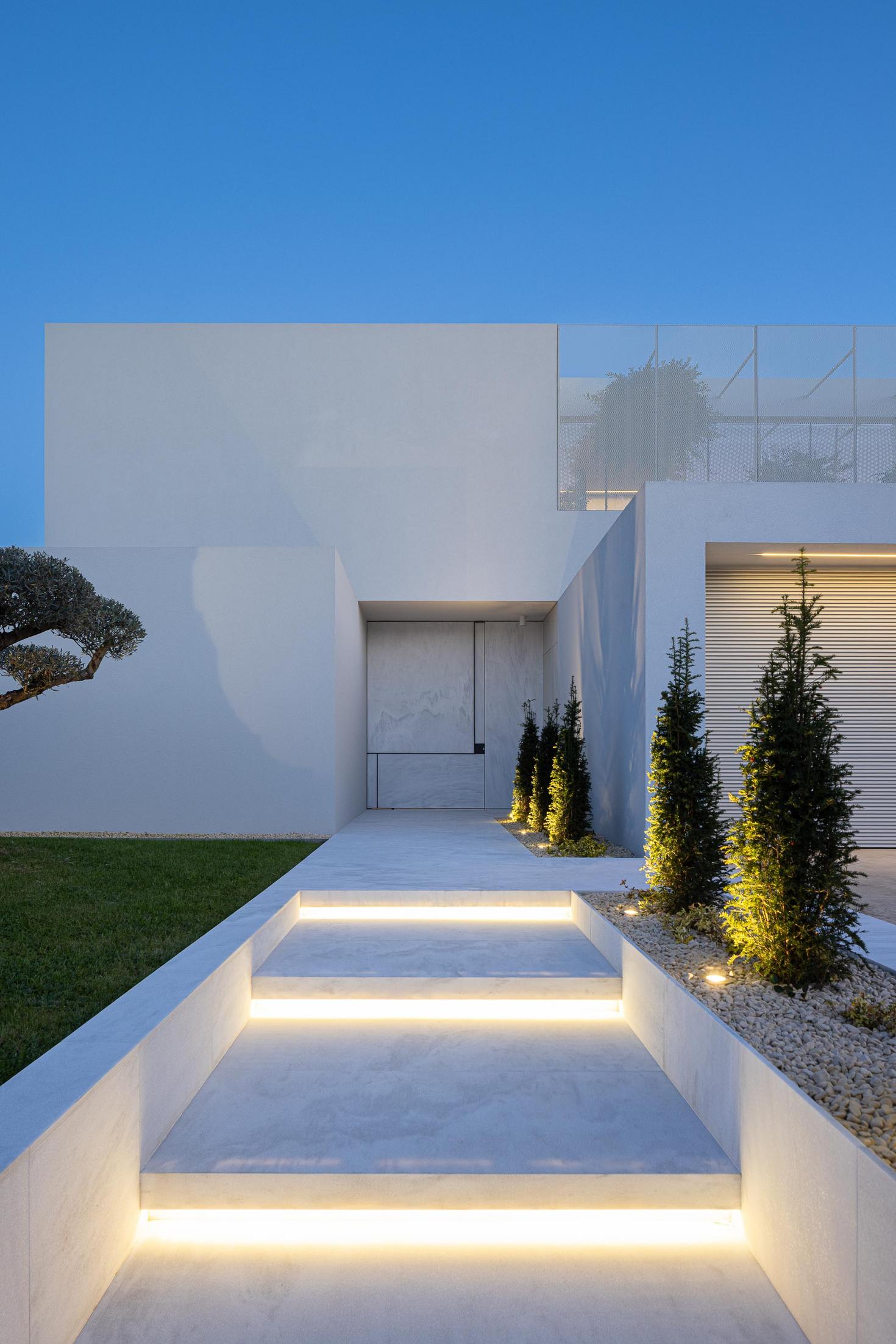 Exterior: Escadaria de acesso à entrada principal, com iluminação embutida e jardim lateral. — Casa Branca Minimalista arquitetura Arquitetura501 em Braga