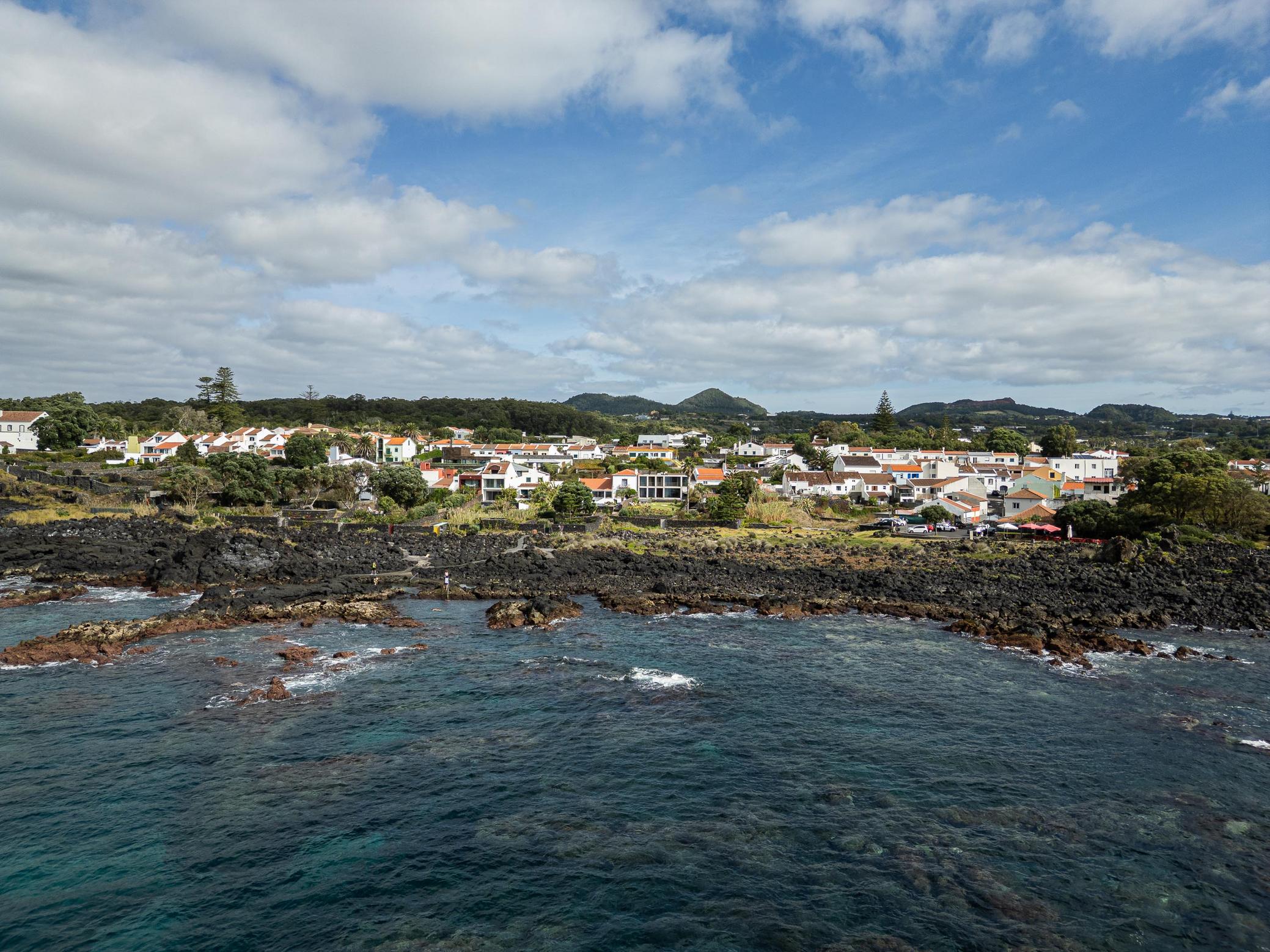 Paisagem: Vista aérea da costa rochosa e casas da vila. Céu azul com nuvens. — Casa da Rocha Quebrada arquitetura SO Arquitetura & Design em São Miguel
