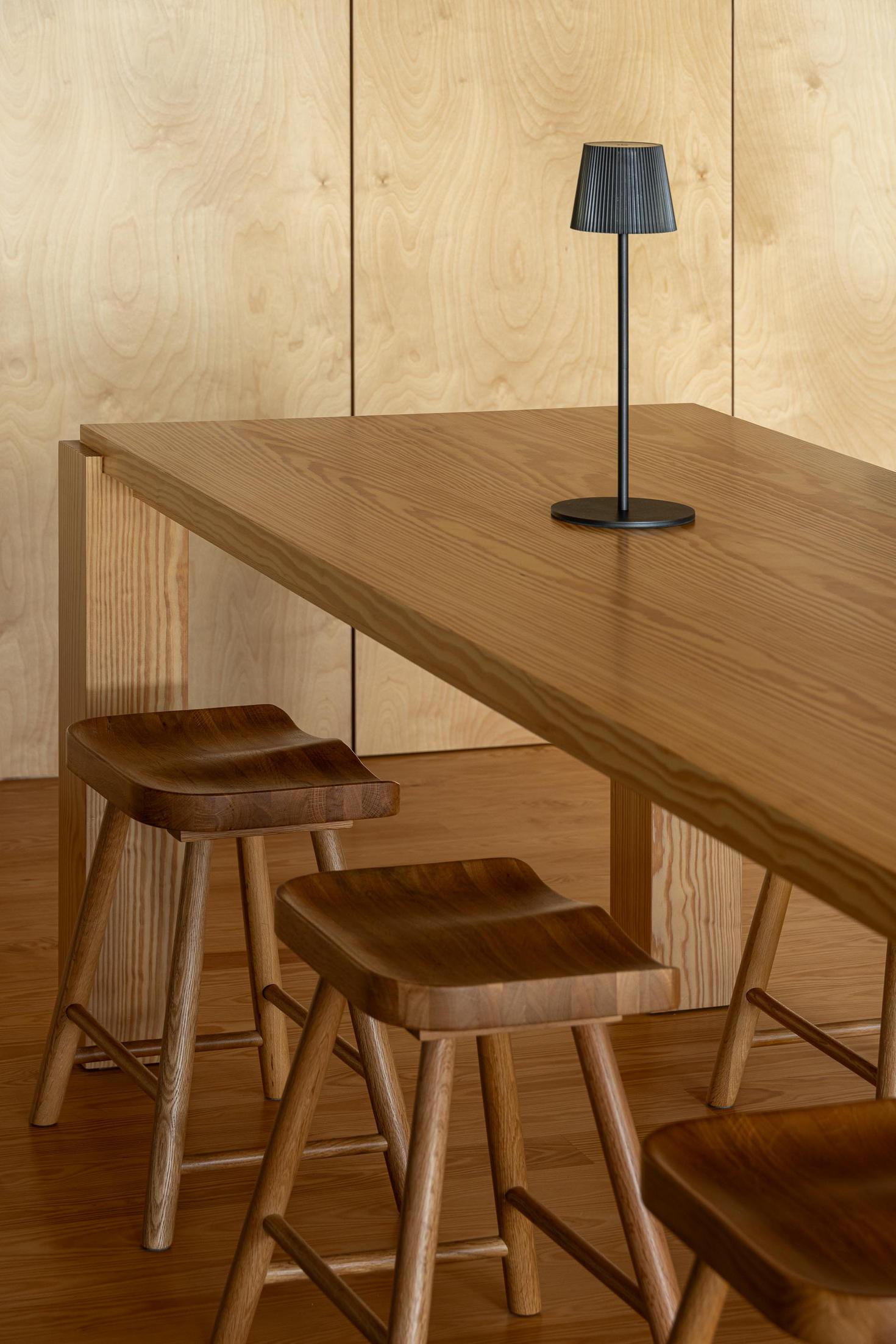 Sala de jantar: Mesa de madeira com bancos e candeeiro. Armários em contraplacado. — Casa da Rocha Quebrada arquitetura SO Arquitetura & Design em São Miguel