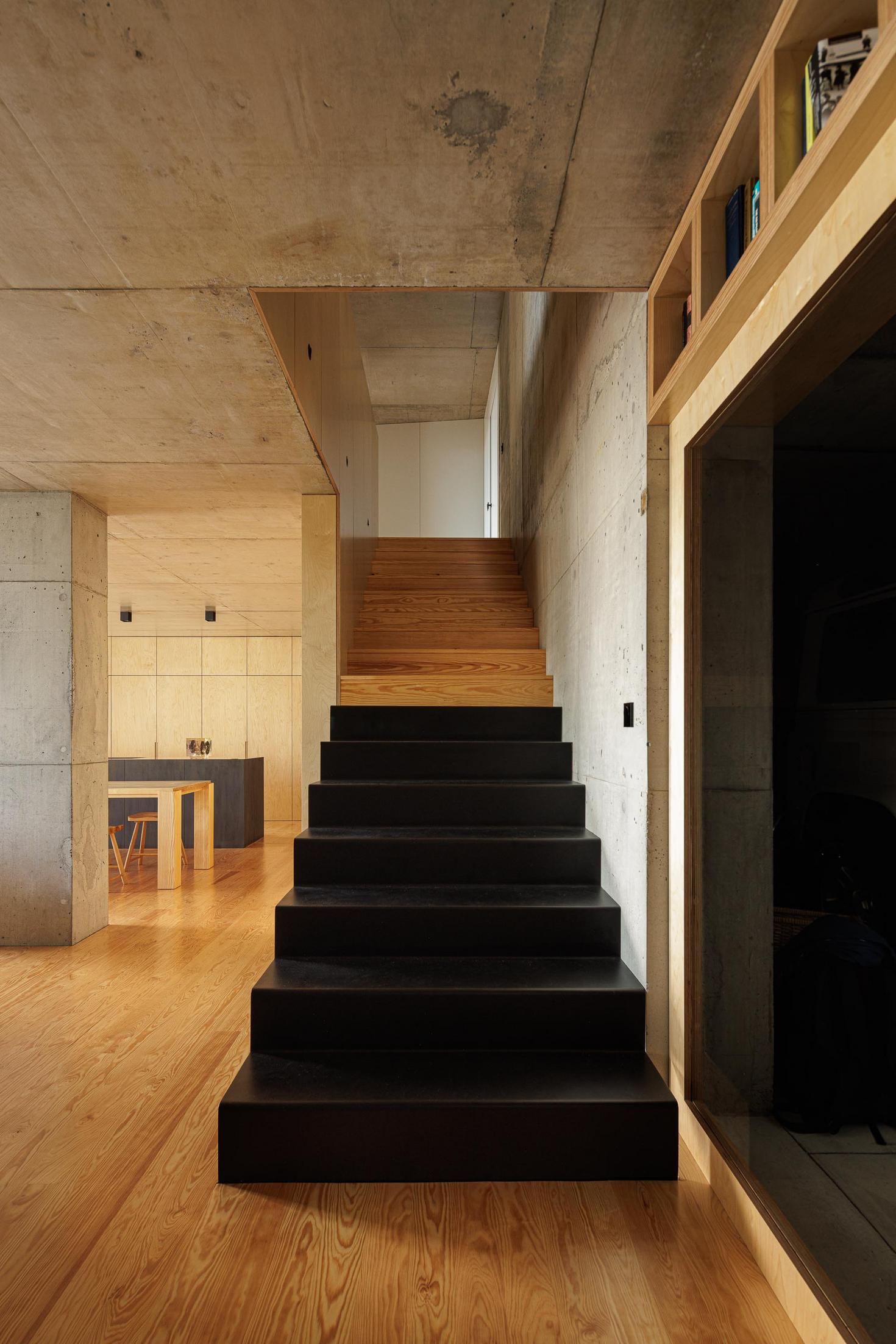 Escadas: Escadas pretas com degraus em madeira. Parede em betão e estantes em madeira. — Casa da Rocha Quebrada arquitetura SO Arquitetura & Design em São Miguel