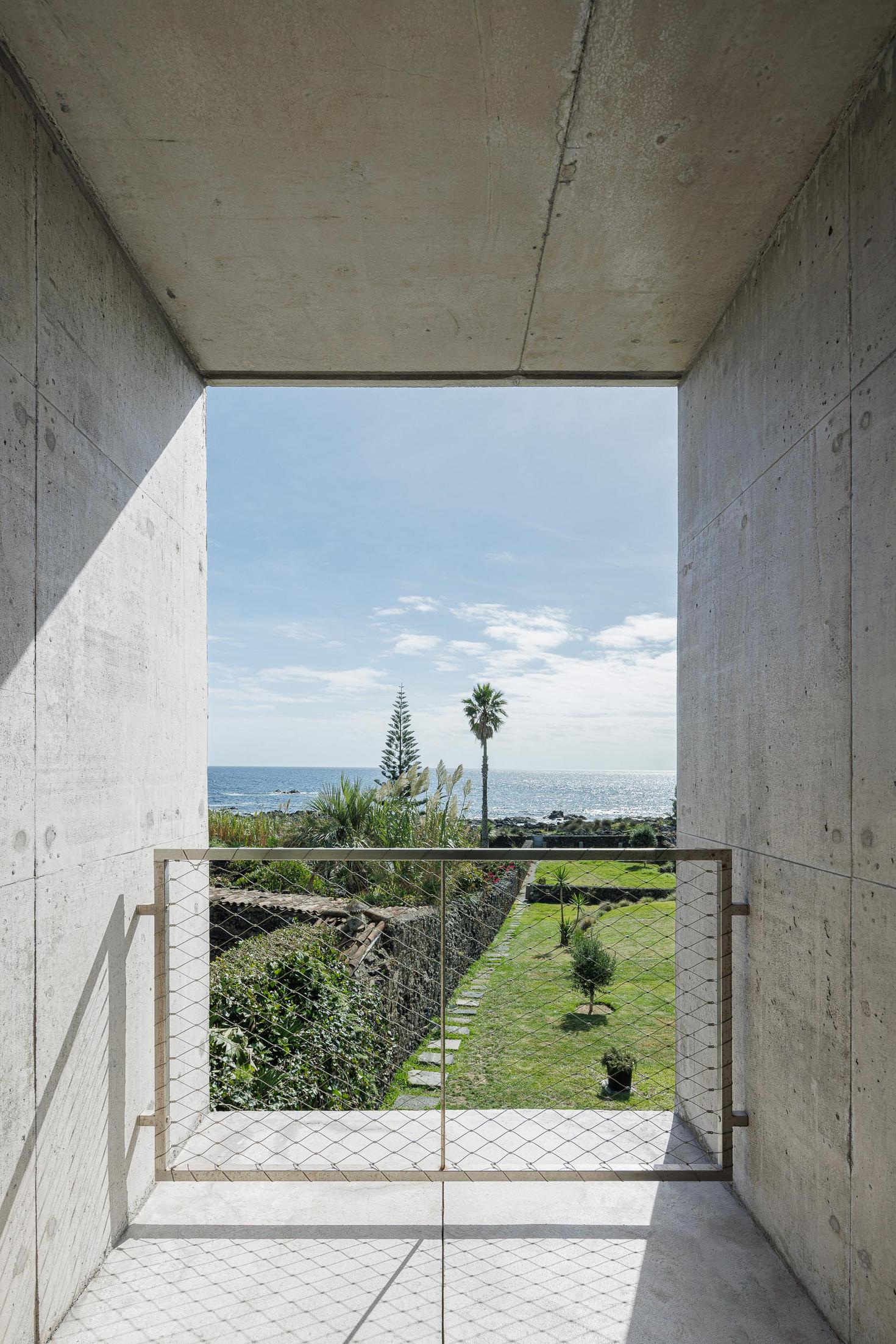 Varanda: Vista para o jardim e mar através da estrutura em betão. Guarda-corpo metálico. — Casa da Rocha Quebrada arquitetura SO Arquitetura & Design em São Miguel