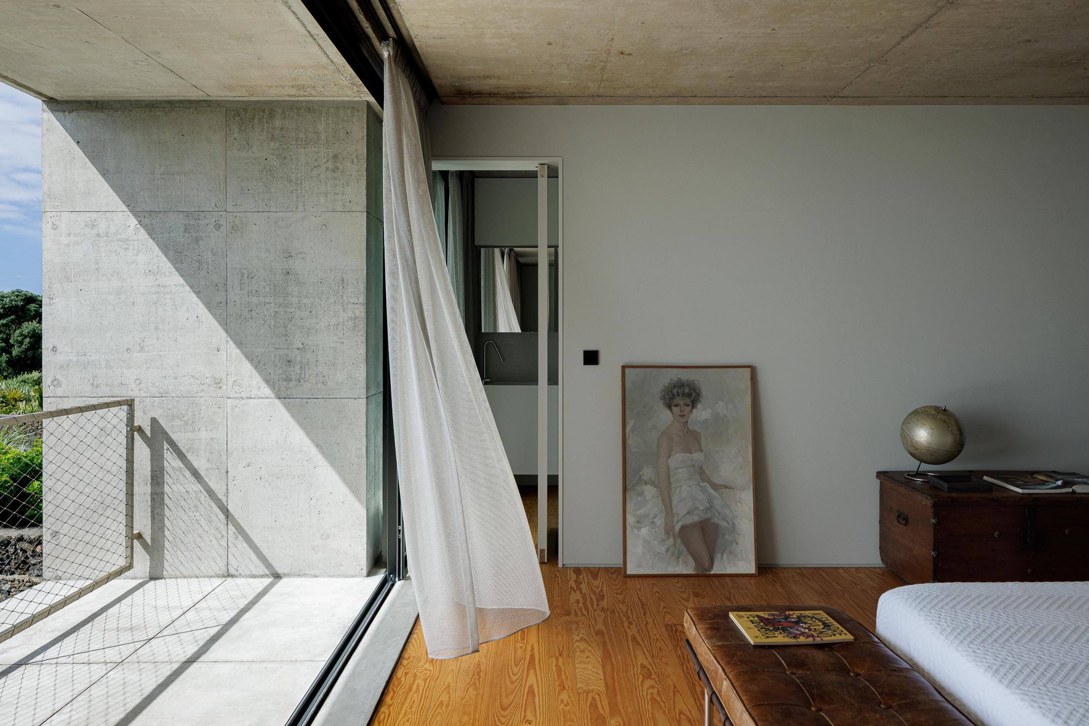 Quarto: Cama branca e casa de banho com porta deslizante. Varanda com vista para o mar. — Casa da Rocha Quebrada arquitetura SO Arquitetura & Design em São Miguel