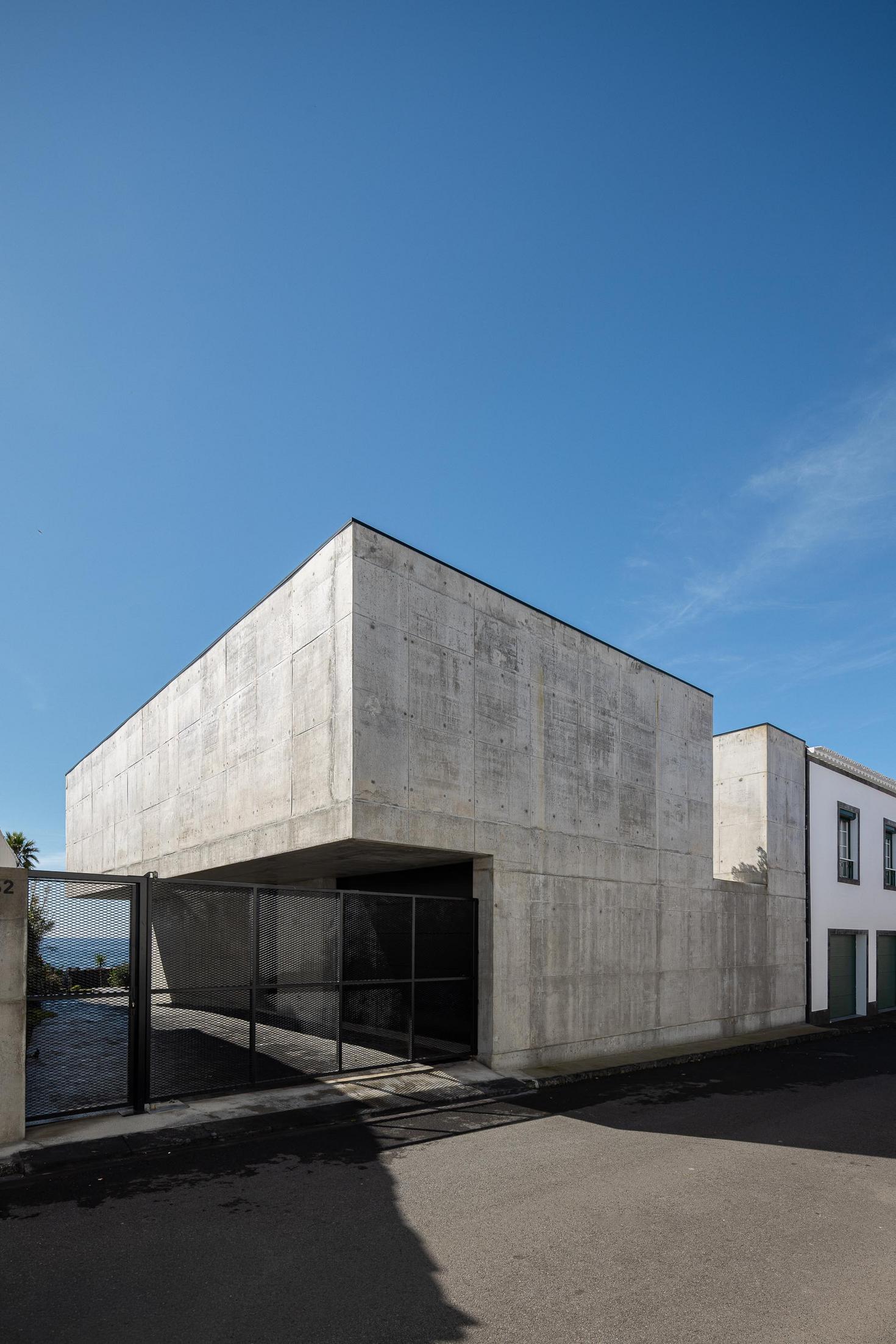 Exterior: Garagem com portão metálico e fachada em betão. Arquitetura moderna. — Casa da Rocha Quebrada arquitetura SO Arquitetura & Design em São Miguel