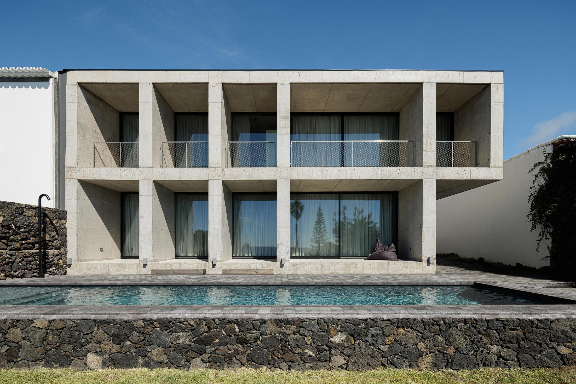 Fachada: Edifício em betão com piscina. Arquitetura minimalista em harmonia com a paisagem. — Casa da Rocha Quebrada arquitetura SO Arquitetura & Design em São Miguel
