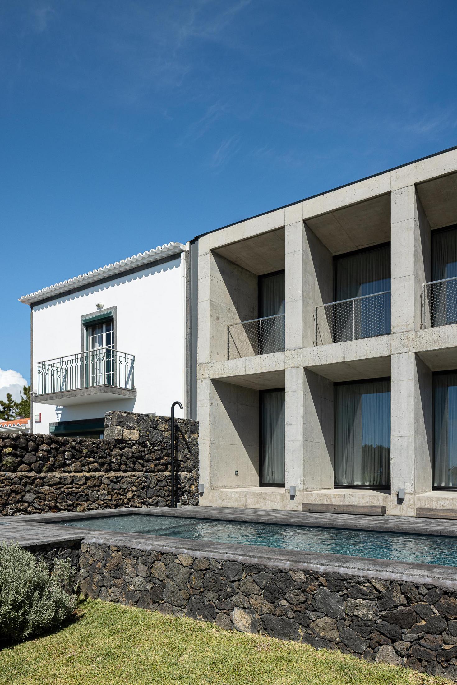 Fachada: Edifício em betão com piscina. Arquitetura moderna contrastando com a casa tradicional. — Casa da Rocha Quebrada arquitetura SO Arquitetura & Design em São Miguel