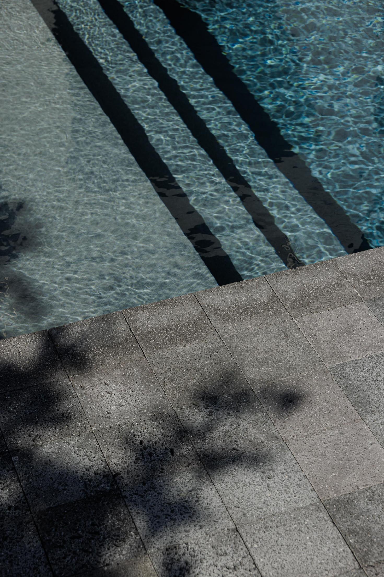 Exterior: Detalhe dos degraus da piscina com pavimento em pedra vulcânica. — Casa da Rocha Quebrada arquitetura SO Arquitetura & Design em São Miguel