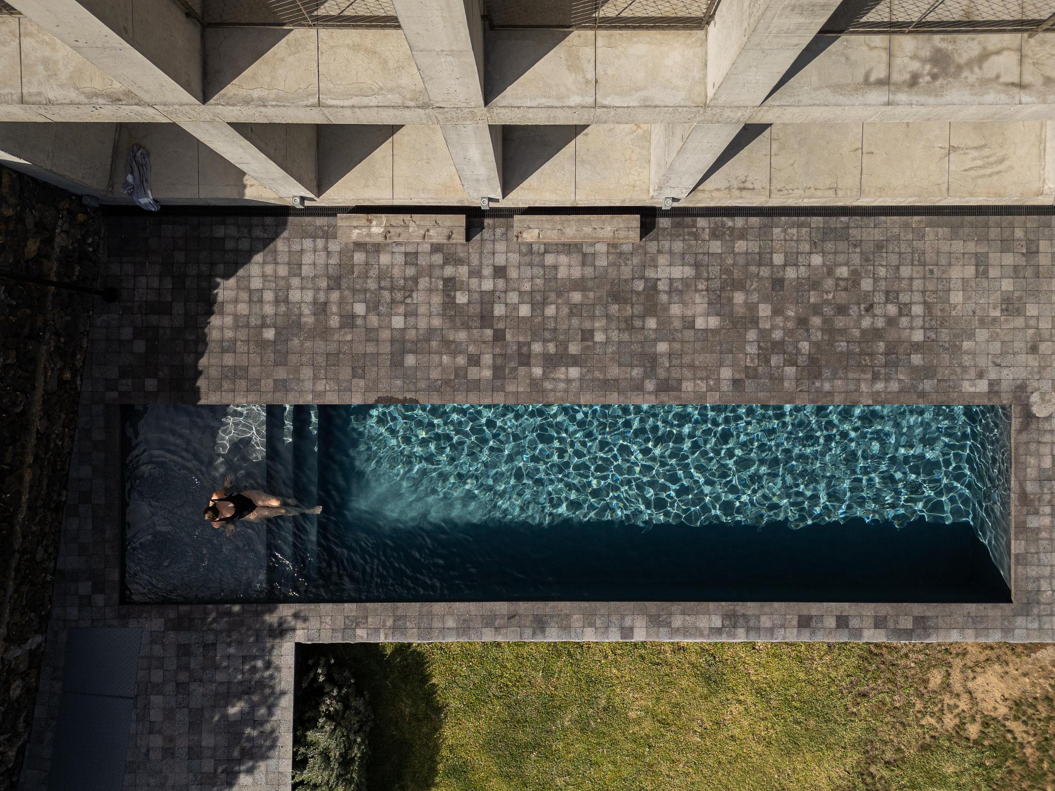 Exterior: Vista aérea da piscina e edifício em betão. Pavimento em pedra e relvado. — Casa da Rocha Quebrada arquitetura SO Arquitetura & Design em São Miguel
