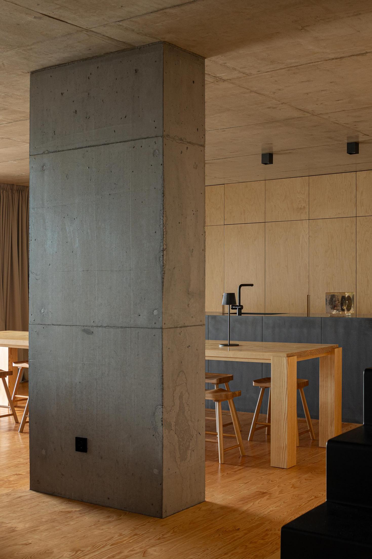 Cozinha: Ilha central e mesa de jantar em madeira. Coluna de betão e armários em contraplacado. — Casa da Rocha Quebrada arquitetura SO Arquitetura & Design em São Miguel