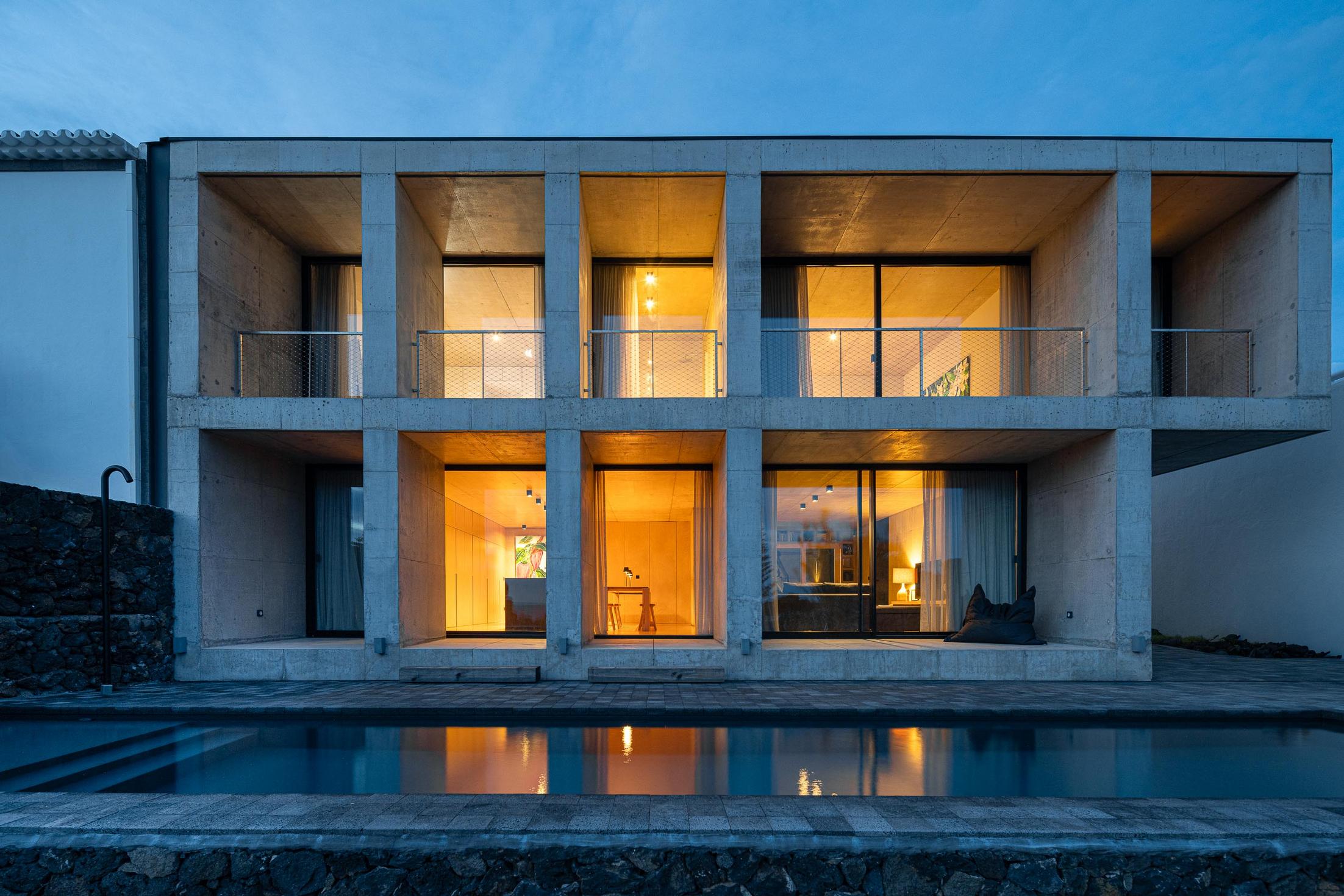 Fachada: Edifício em betão com piscina. Iluminação noturna realça a arquitetura minimalista. — Casa da Rocha Quebrada arquitetura SO Arquitetura & Design em São Miguel