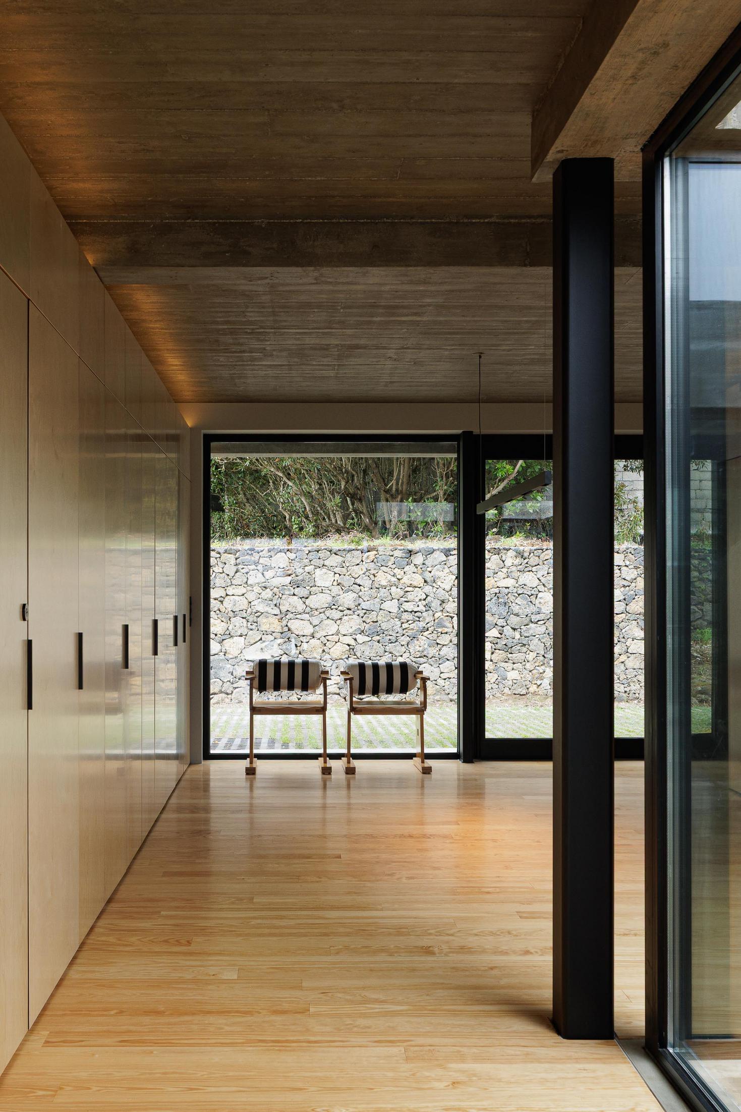 Corredor: Armários em contraplacado, pavimento em madeira e cadeiras de madeira com padrão listrado ao fundo. — Casa CR arquitetura SO Arquitetura & Design em São Miguel
