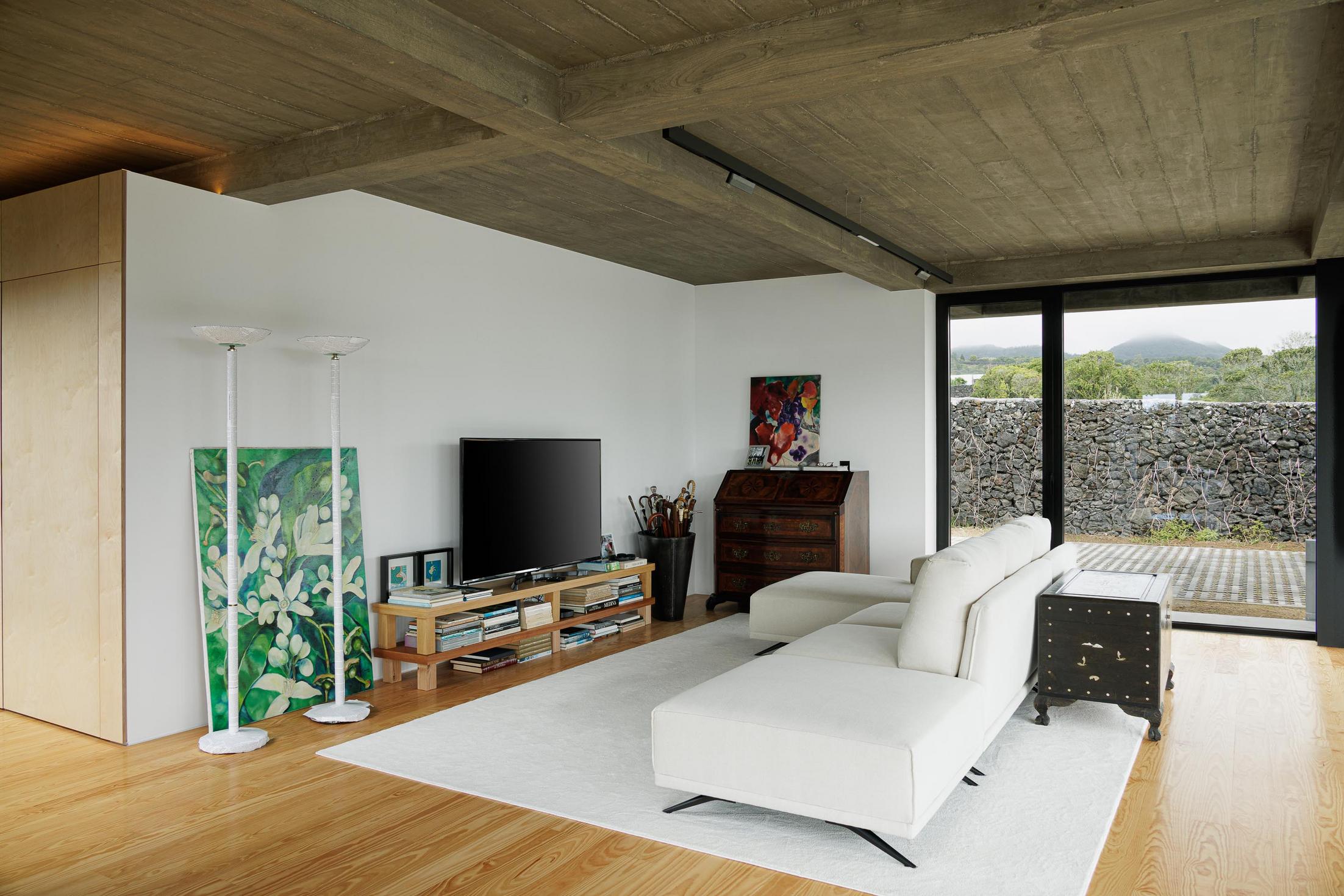 Sala de estar: Sofá branco, televisão e móveis antigos. Alcatifa branca e pavimento em madeira. — Casa CR arquitetura SO Arquitetura & Design em São Miguel