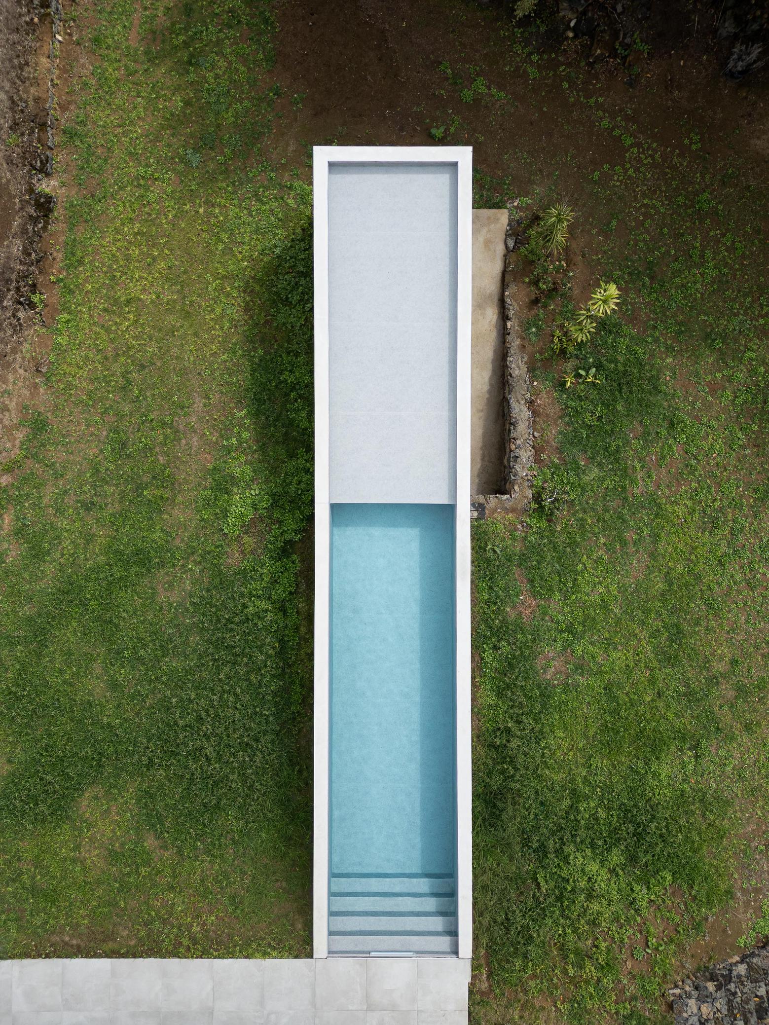 Exterior: Vista aérea da piscina retangular com borda em betão e relvado circundante. — Casa CR arquitetura SO Arquitetura & Design em São Miguel