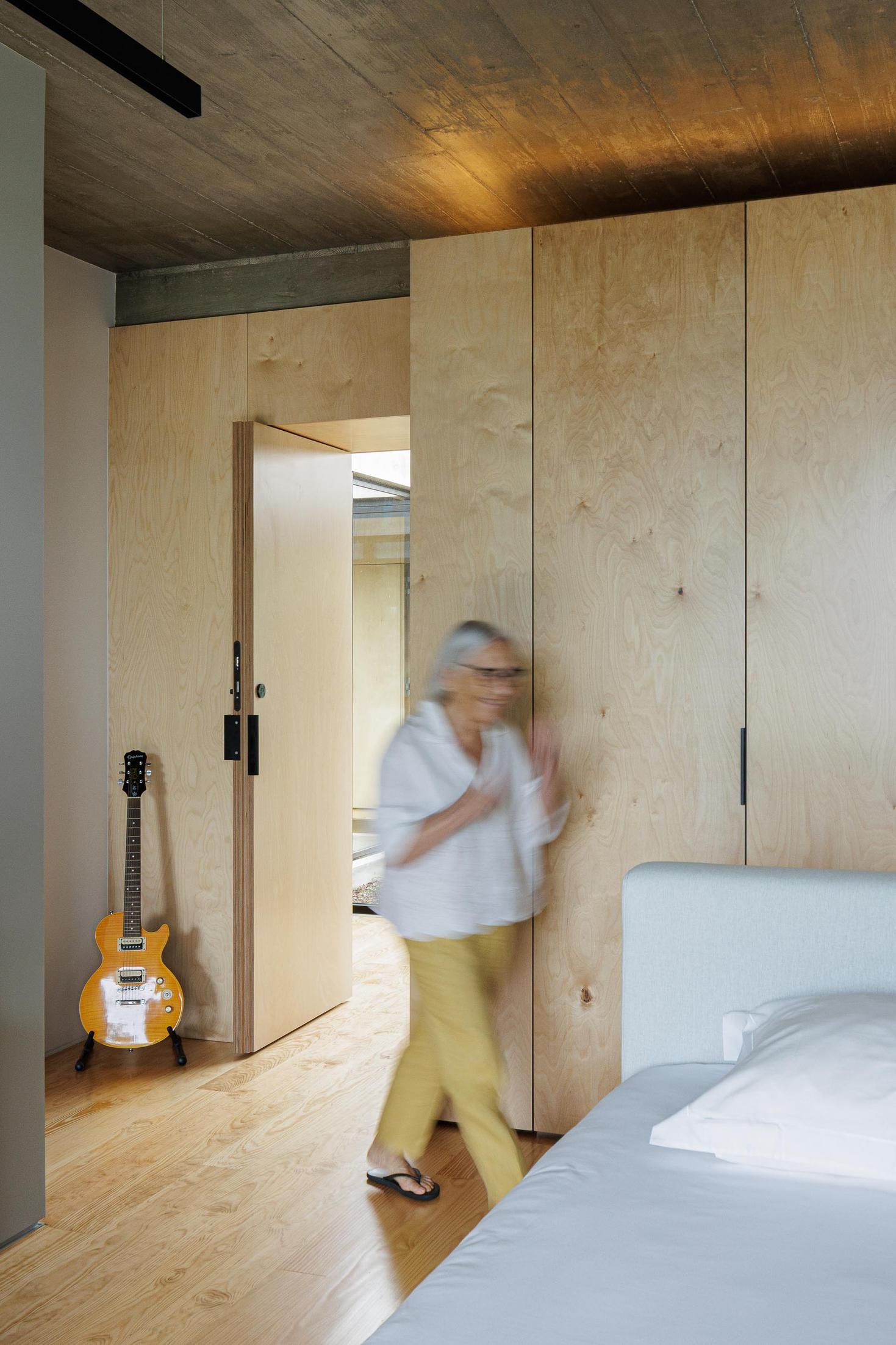 Quarto: Roupeiro em contraplacado, pavimento em madeira e guitarra elétrica. — Casa CR arquitetura SO Arquitetura & Design em São Miguel