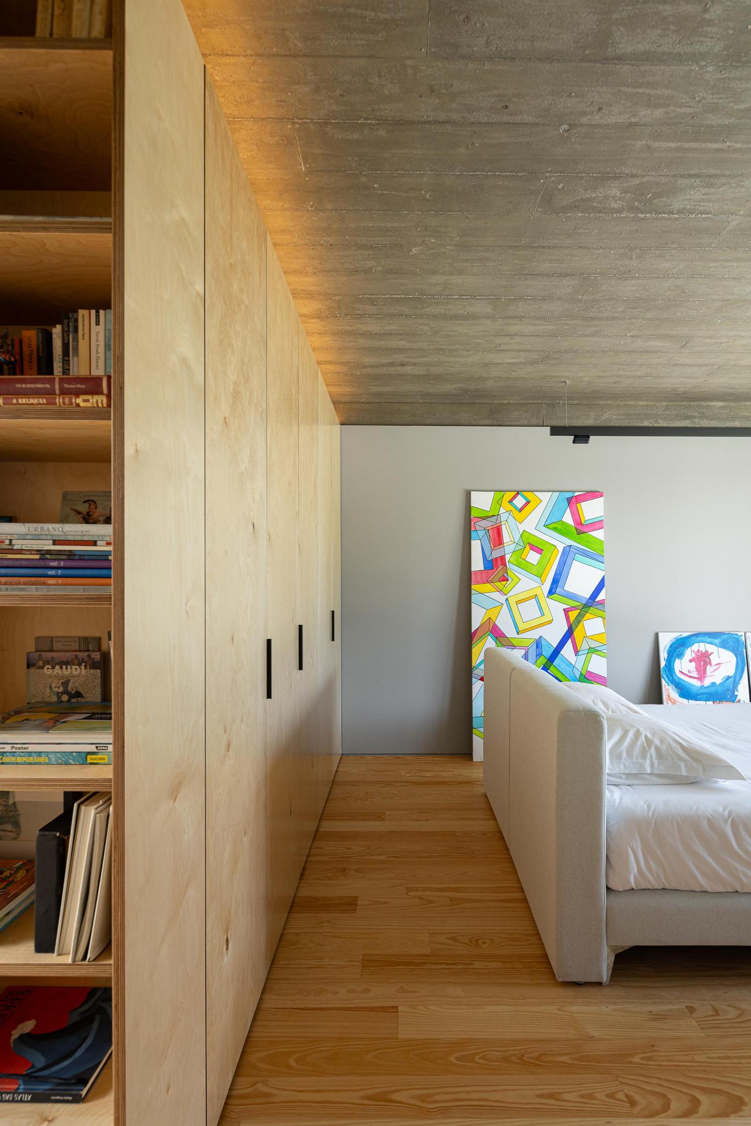 Quarto: Roupeiro em contraplacado com estante, pavimento em madeira e pintura abstrata. — Casa CR arquitetura SO Arquitetura & Design em São Miguel