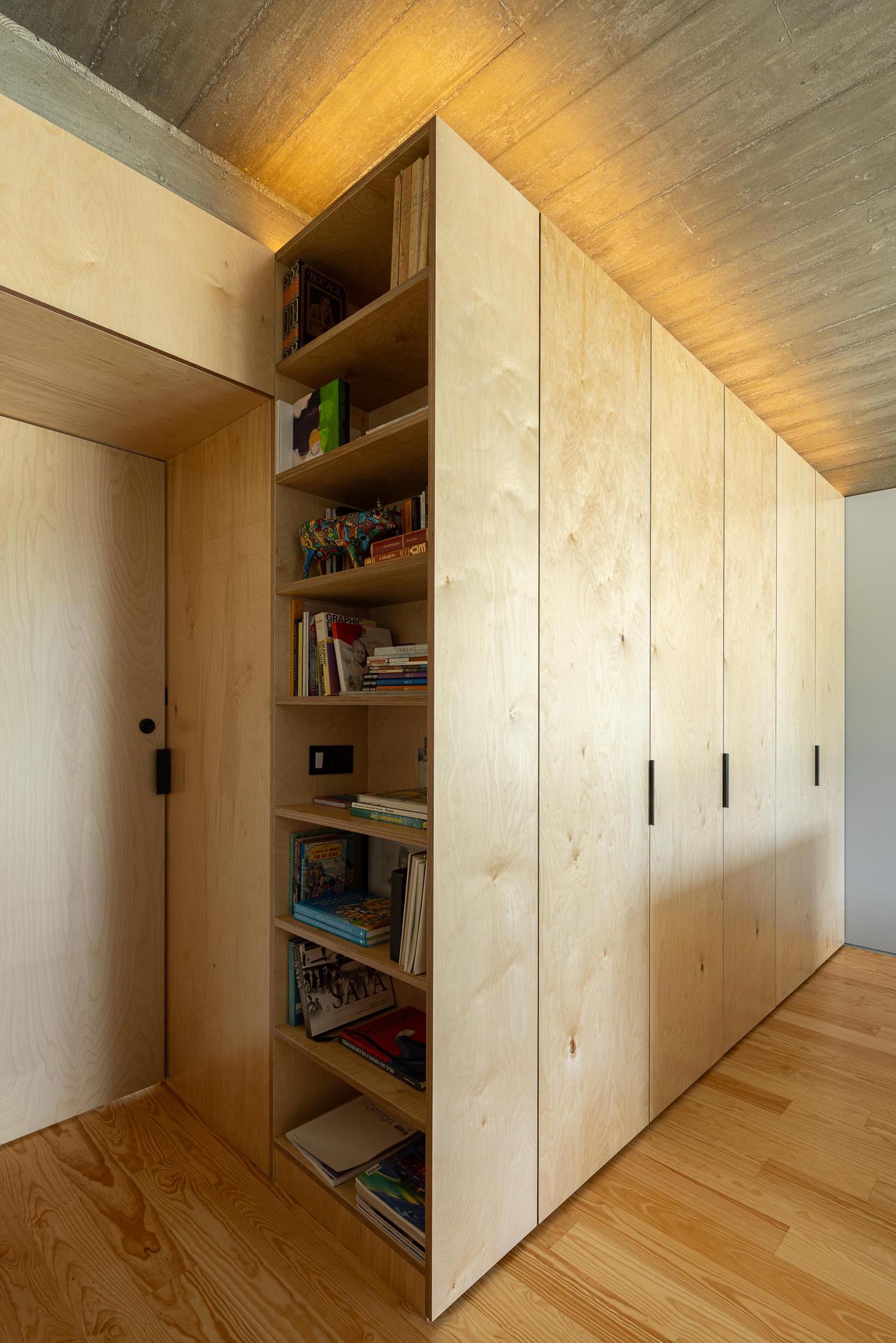 Quarto: Roupeiro em contraplacado com estante, pavimento em madeira e porta em contraplacado. — Casa CR arquitetura SO Arquitetura & Design em São Miguel