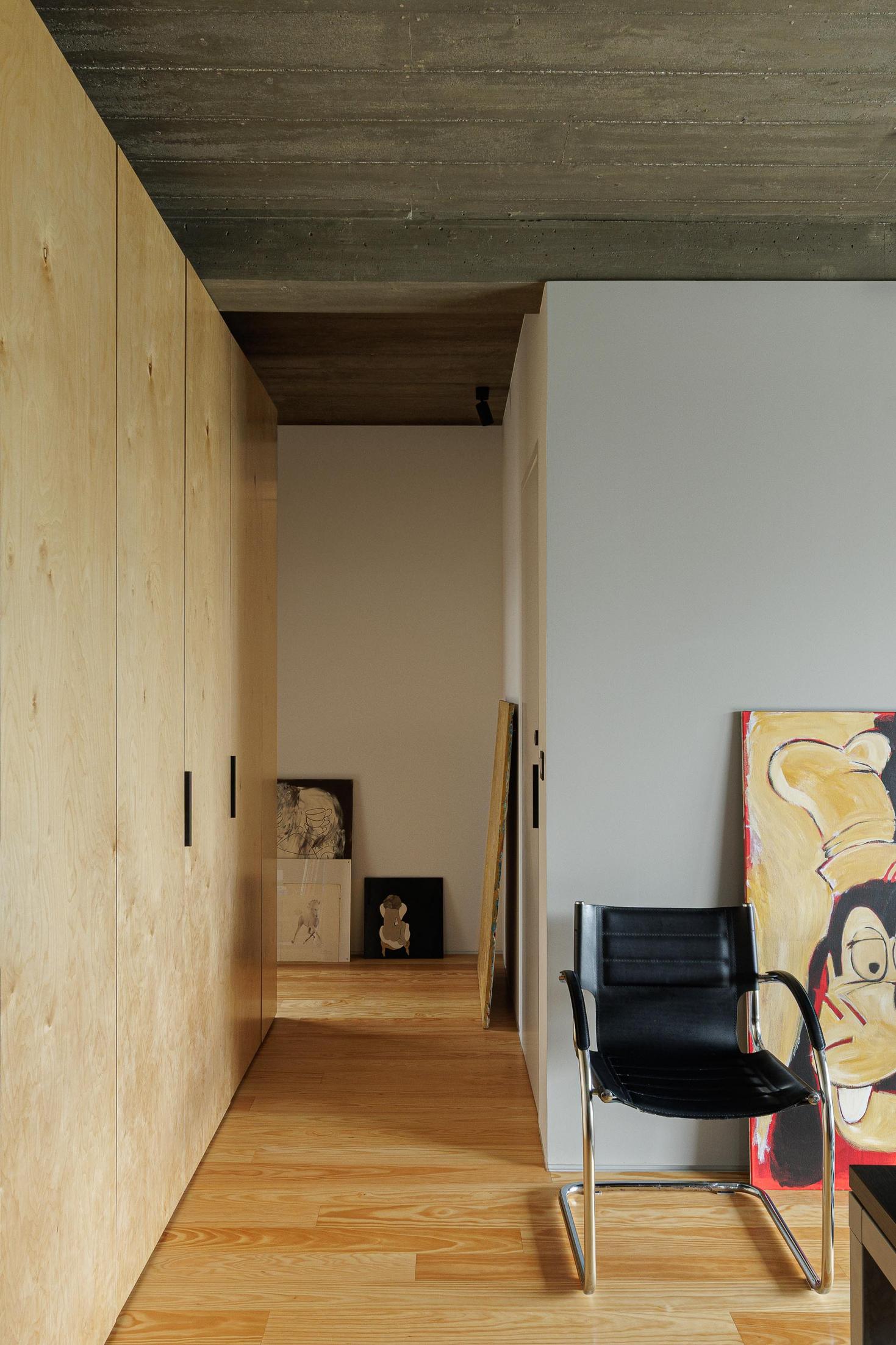 Quarto: Roupeiro em contraplacado, pavimento em madeira e cadeira preta. — Casa CR arquitetura SO Arquitetura & Design em São Miguel