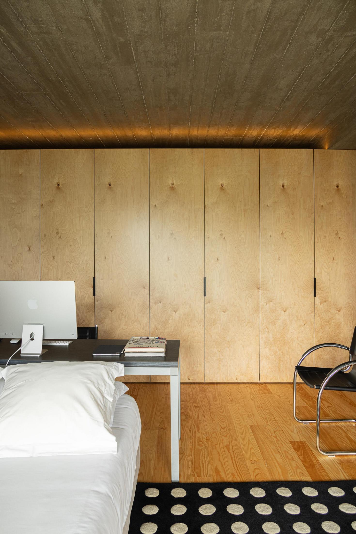 Quarto: Roupeiro em contraplacado, pavimento em madeira e secretária com computador. — Casa CR arquitetura SO Arquitetura & Design em São Miguel