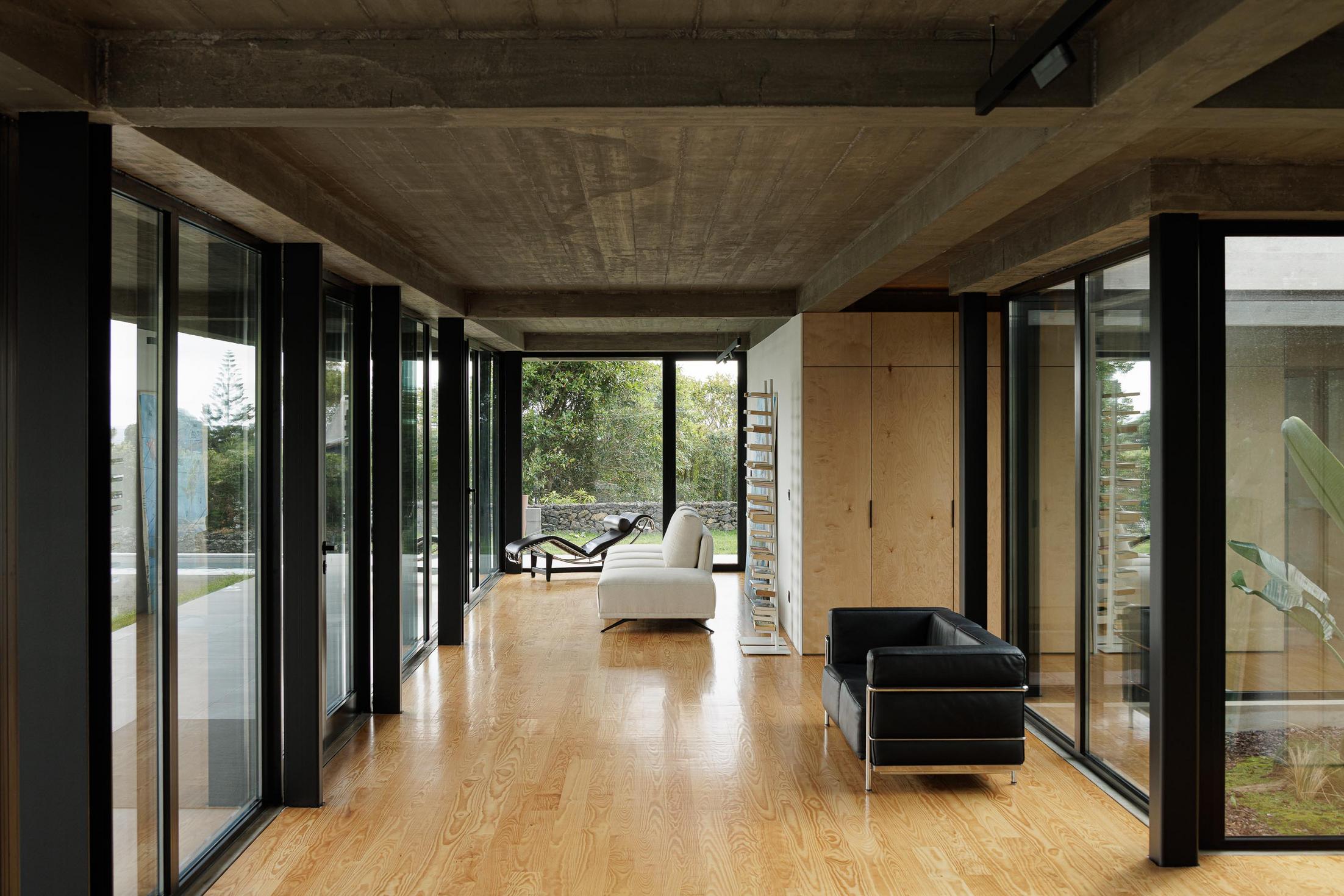 Sala de estar: Grandes janelas, sofá branco e chaise longue. Pátio interior com vegetação. — Casa CR arquitetura SO Arquitetura & Design em São Miguel