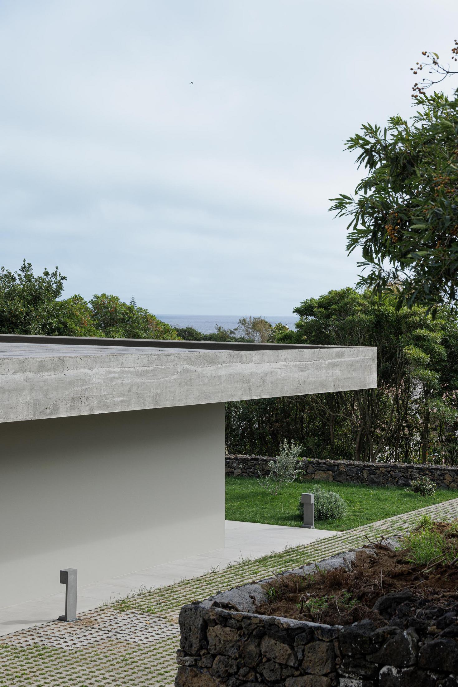 Exterior: Fachada da casa com teto em betão aparente e relvado. — Casa CR arquitetura SO Arquitetura & Design em São Miguel
