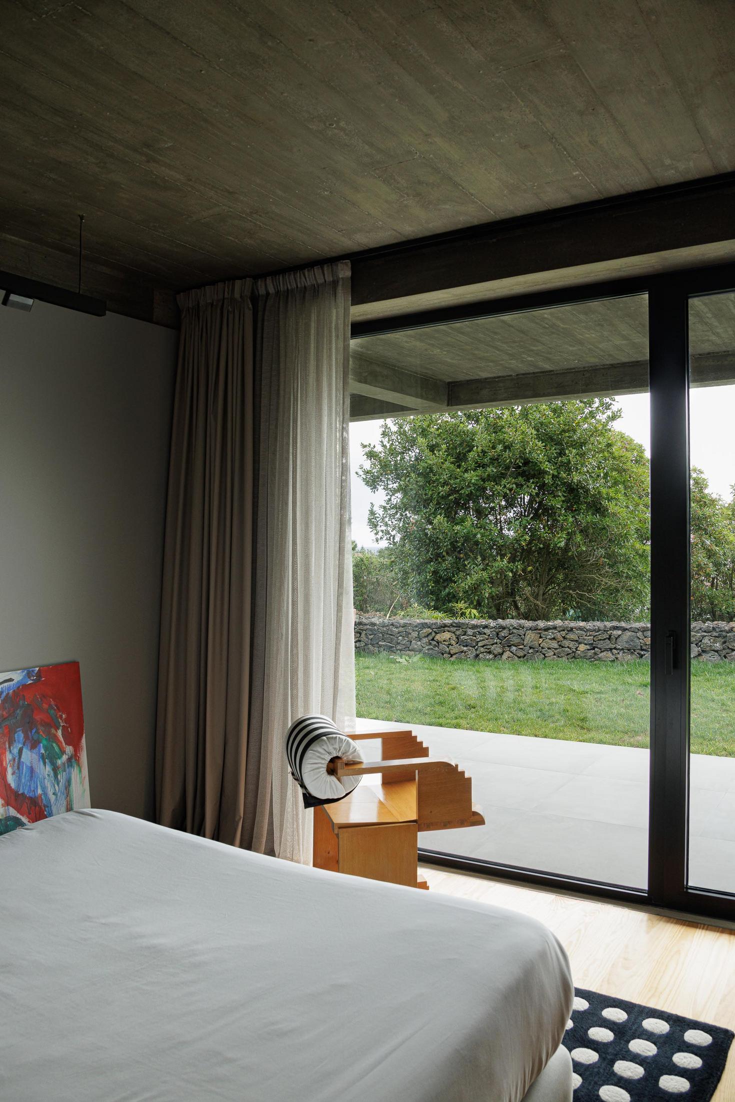 Quarto: Cama branca, cadeira de madeira e alcatifa com padrão de bolas. — Casa CR arquitetura SO Arquitetura & Design em São Miguel