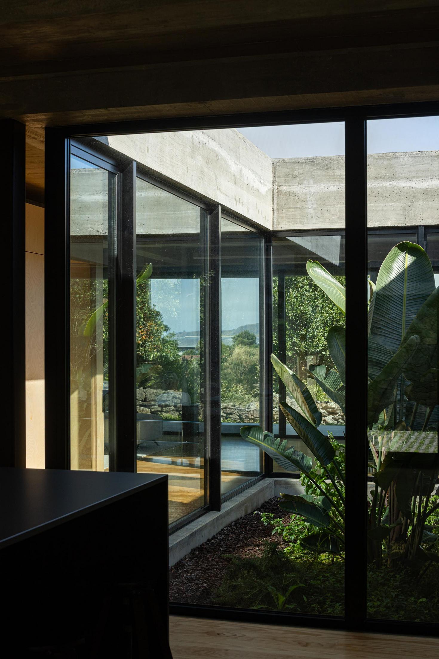 Pátio interior: Vegetação tropical vista através das janelas da casa. — Casa CR arquitetura SO Arquitetura & Design em São Miguel