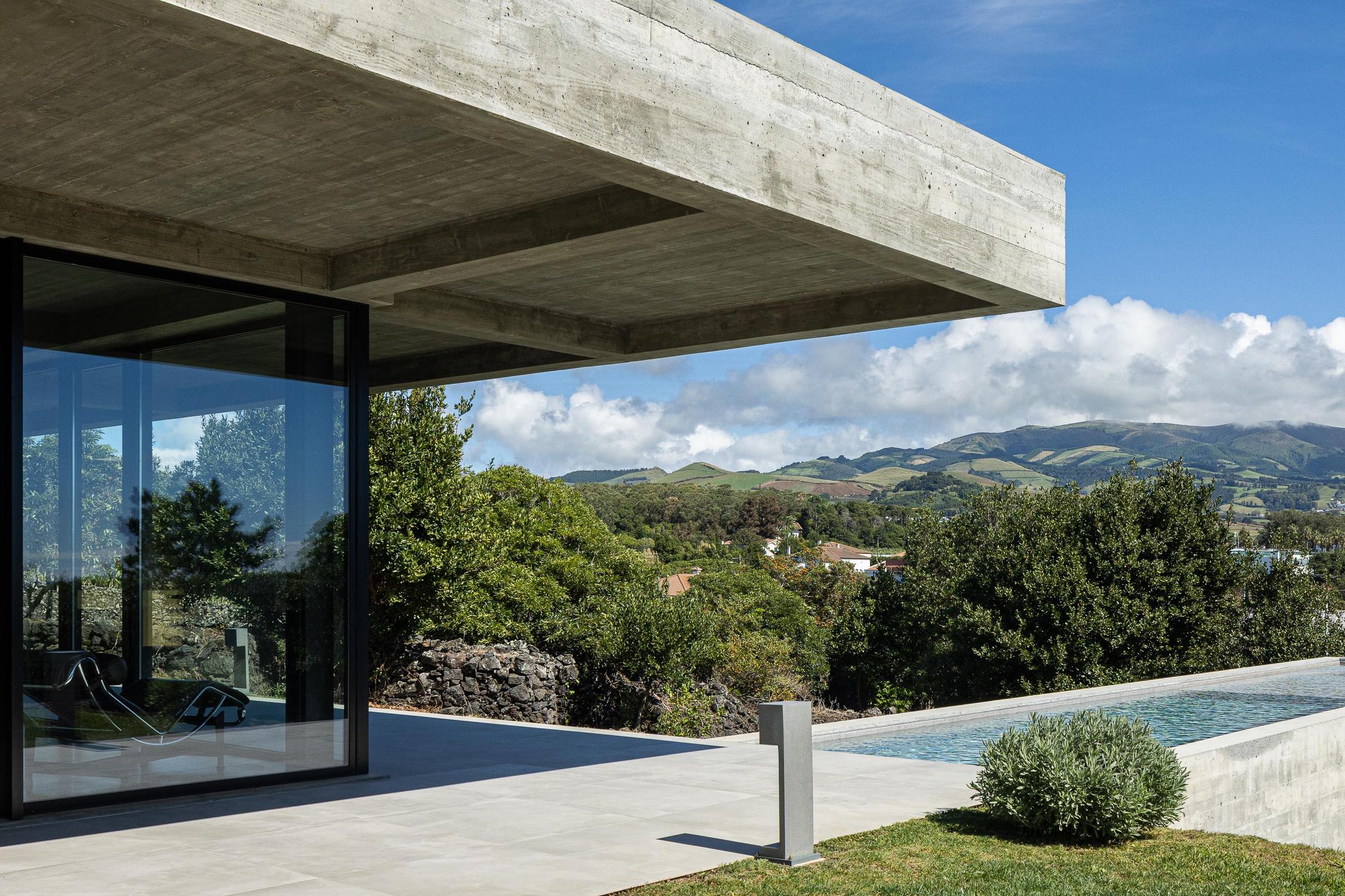 Exterior: Fachada da casa com teto em betão aparente e piscina. — Casa CR arquitetura SO Arquitetura & Design em São Miguel