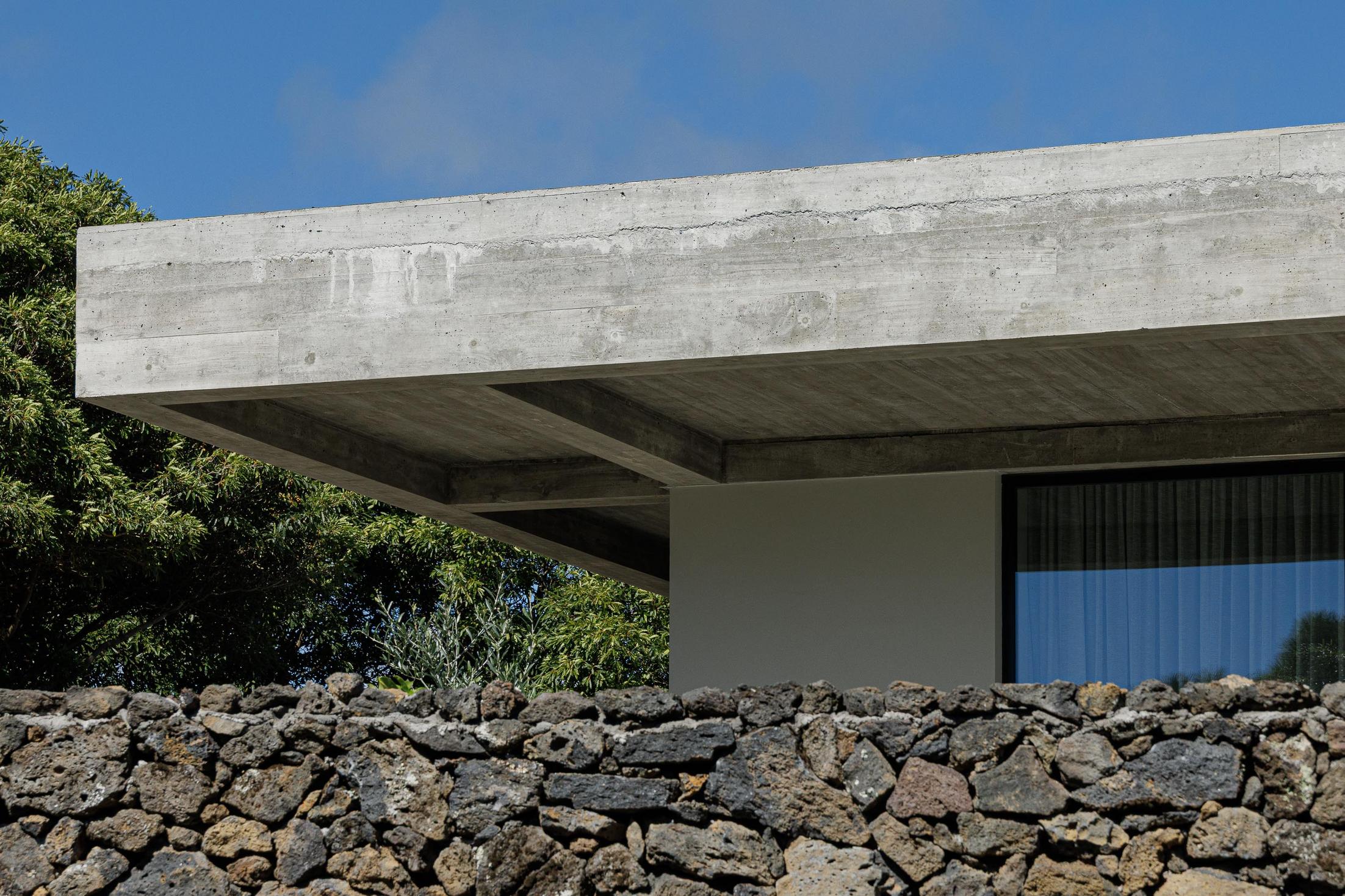 Exterior: Teto em betão aparente e muro de pedra vulcânica. — Casa CR arquitetura SO Arquitetura & Design em São Miguel